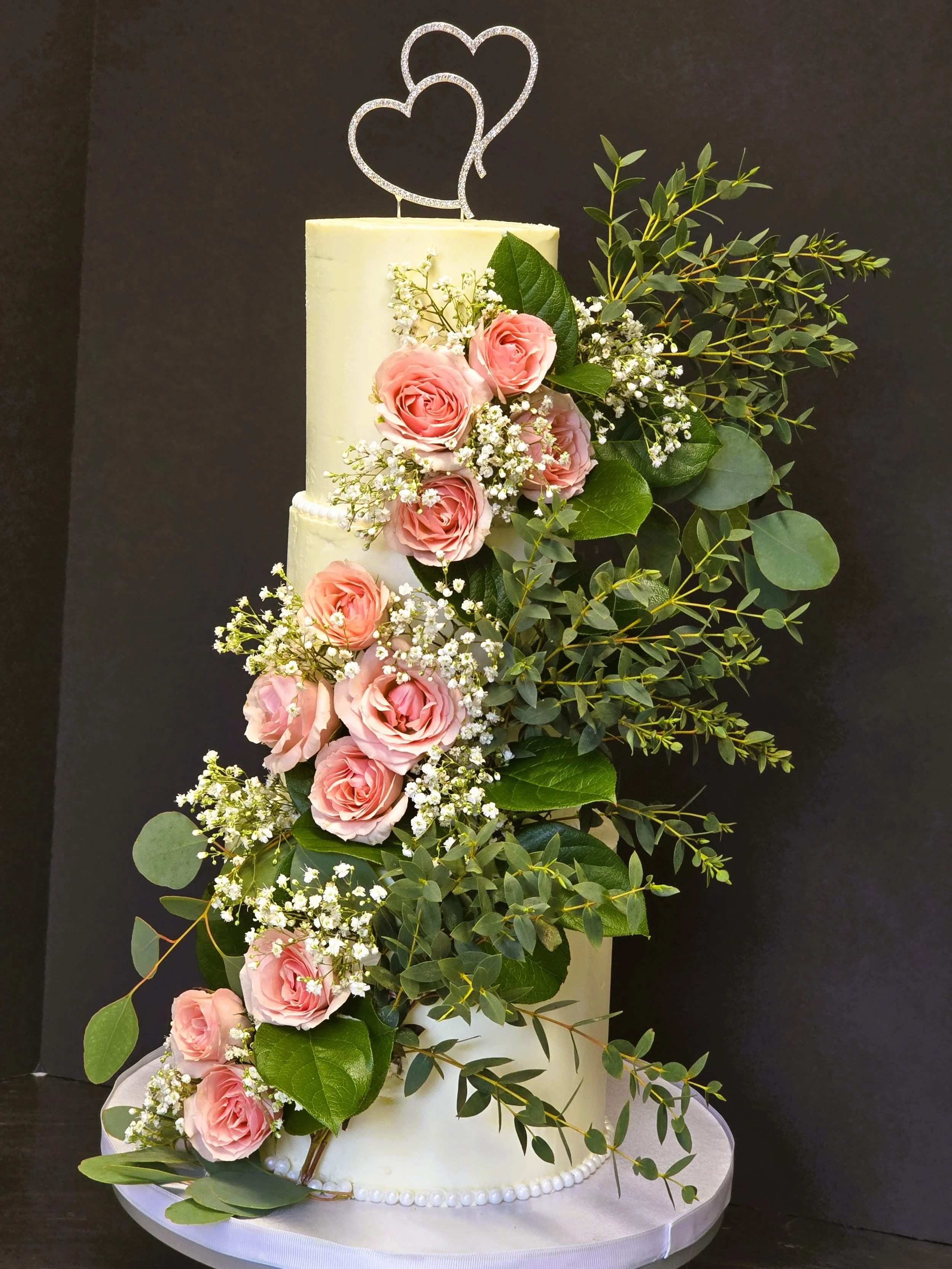 The cake under the flowers was simple and elegant. The natural flowers flowing in a rich cascade created an impressive bouquet that almost made the bride cry when she saw it before the ceremony. We work with local florists, and this was Janet's Flora