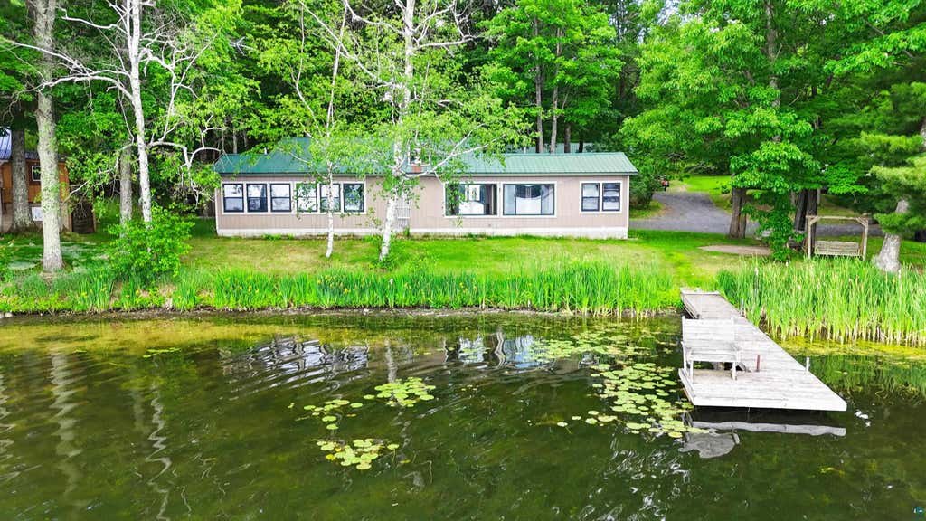 Welcome to 6030 Lake Ahmeek Road - a lakefront retreat on 1.5 wooded acres with 100 feet of sandy shoreline on Iron Lake. The home sits just steps from the water, with no road between you and the beach. Inside, a spacious living room stretches along 