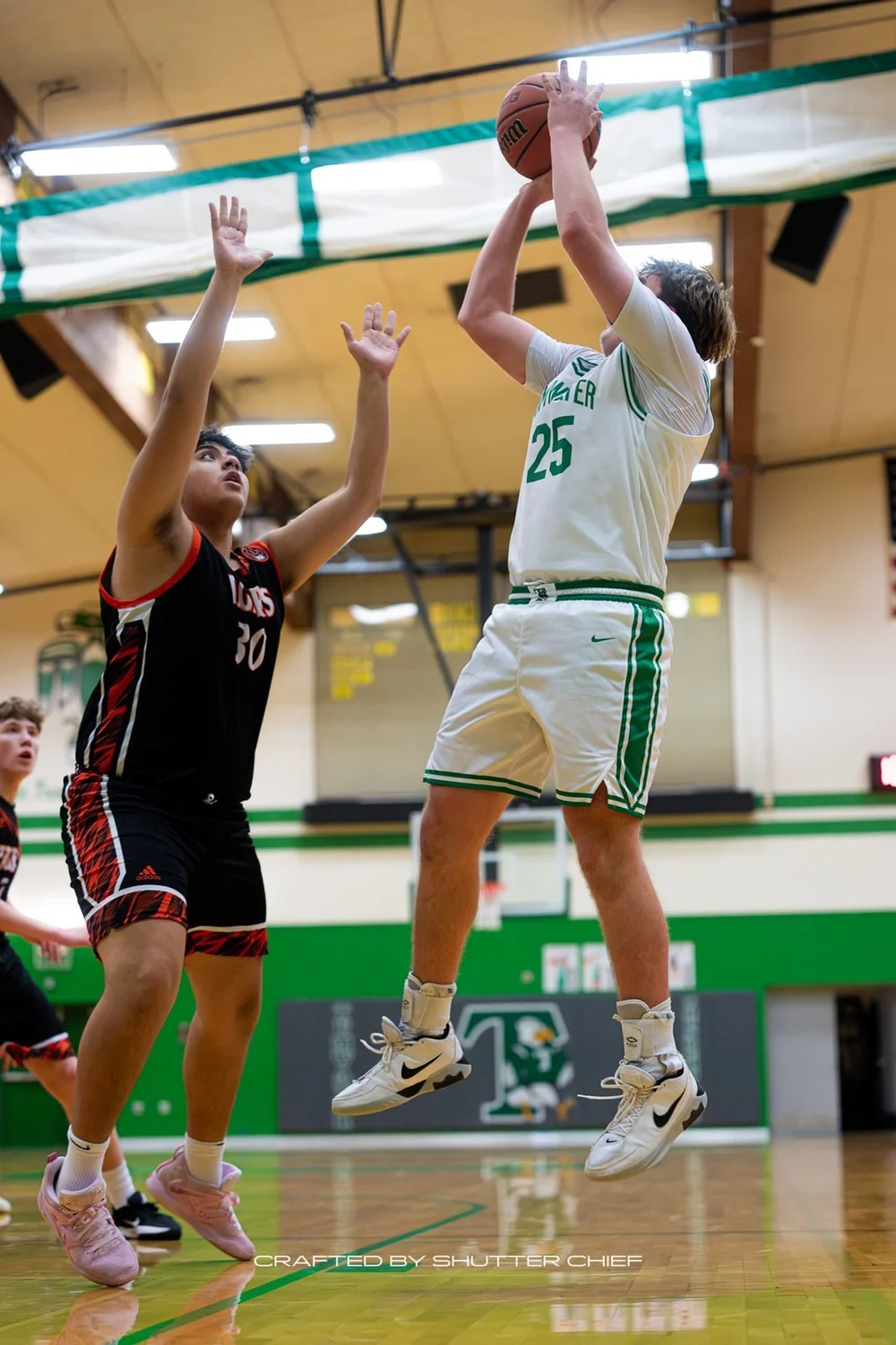 Basketball player rising for a shot beside a defender