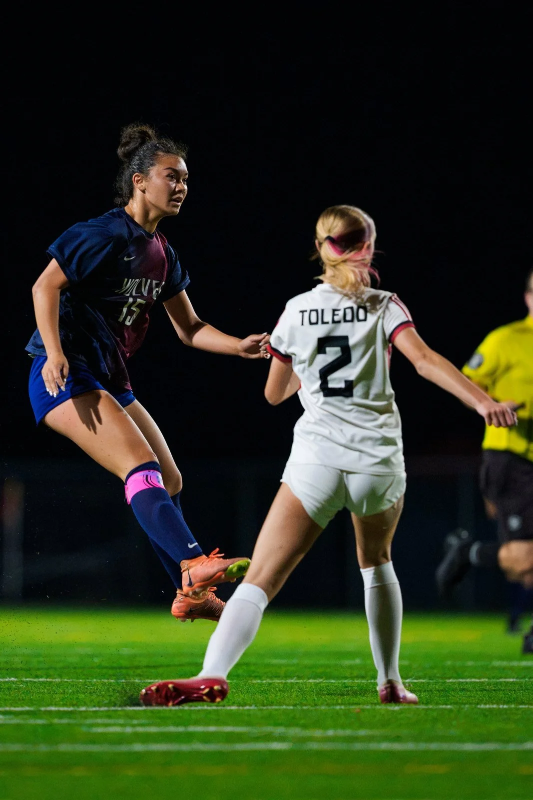 Soccer players contesting the ball under stadium lights