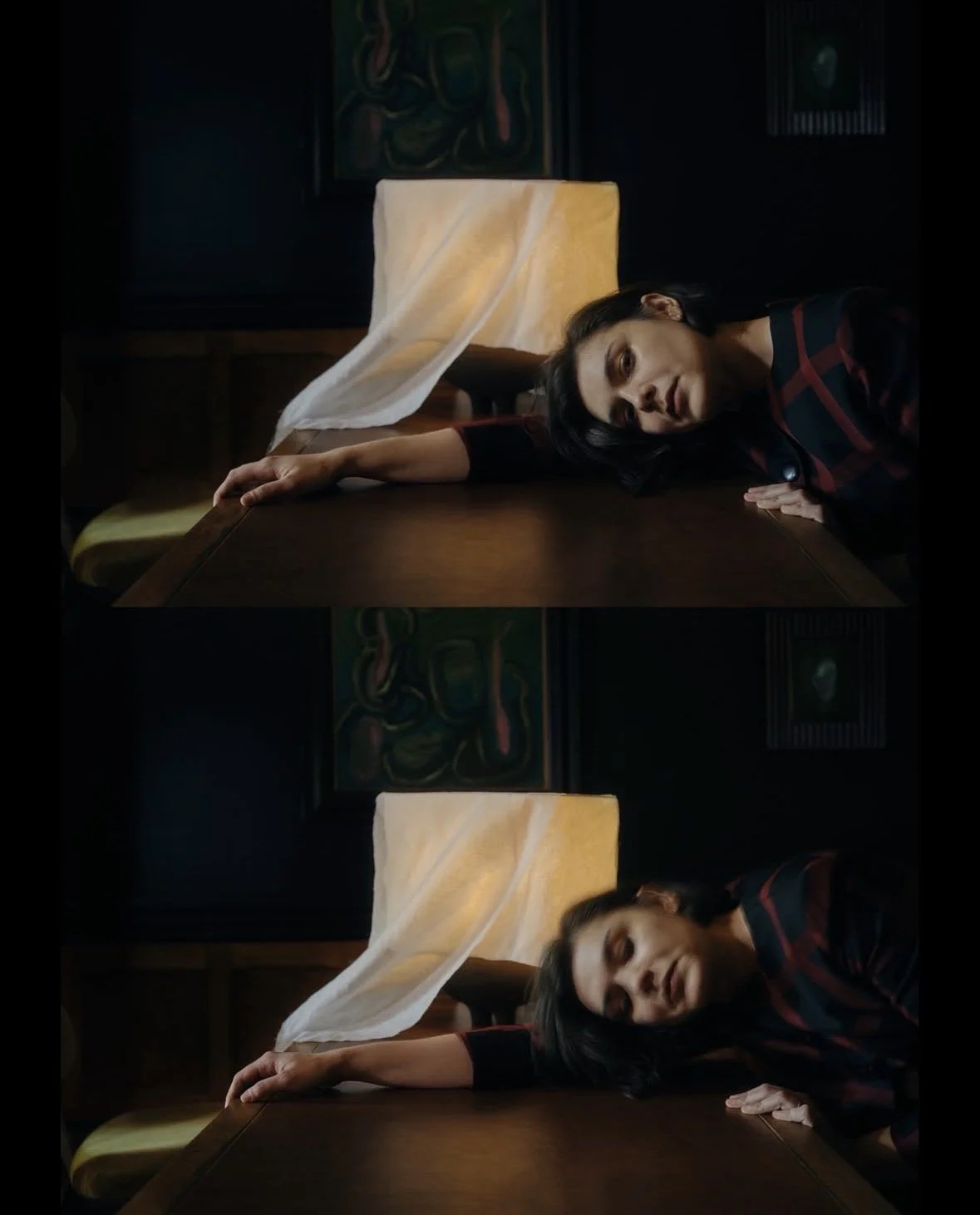 Woman laying on a table with her arm hanging off, in a dimly lit room with artwork on the wall behind her.
