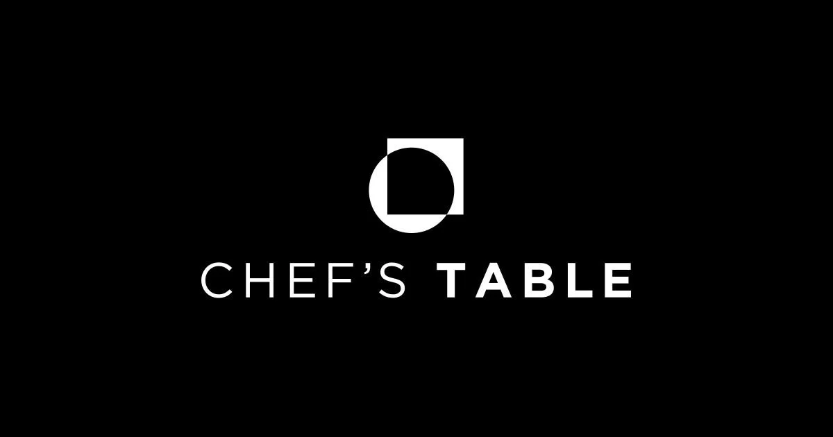 Black background with white geometric logo above the text 'CHEF'S TABLE' in white capital letters.