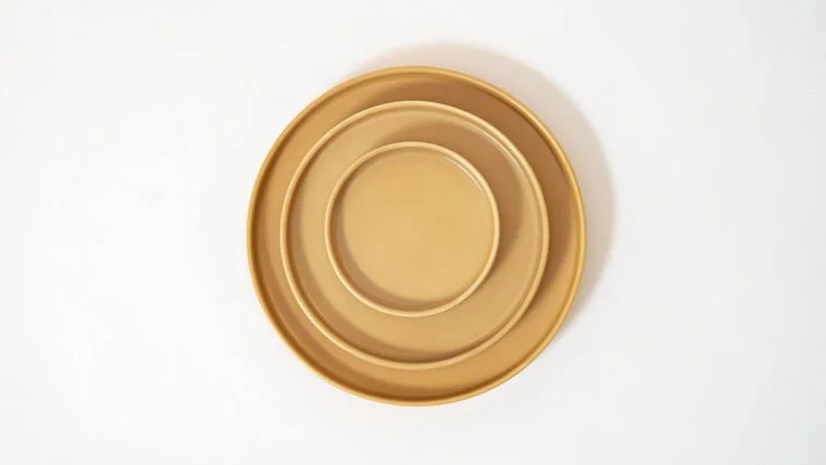 Three nested round golden plates on a white background.