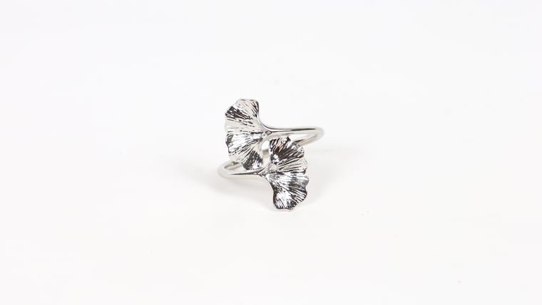 Silver ring with a design resembling ginkgo leaves on a plain white background.
