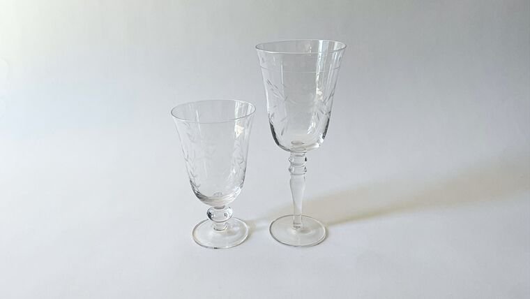 Two clear glass goblets, one small and one tall, with etched designs on a plain white background.