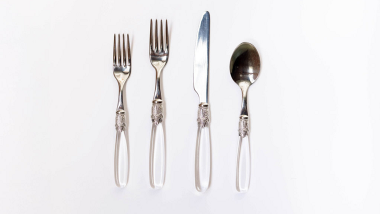 A set of four silver utensils with ornate white handles: two forks, a knife, and a spoon, arranged on a white background.