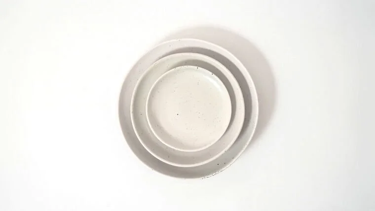Three white ceramic bowls stacked inside each other on a white surface.