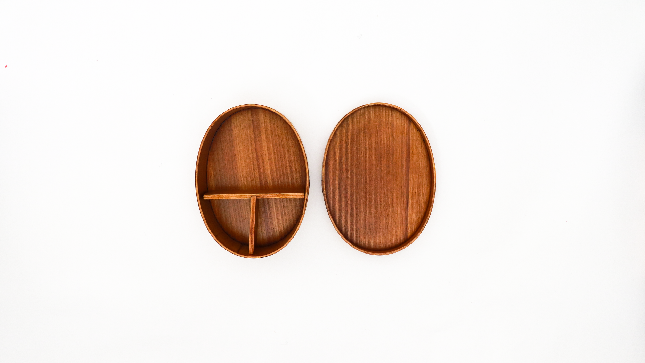 Two oval wooden trays on a white background, one with compartments and one plain.