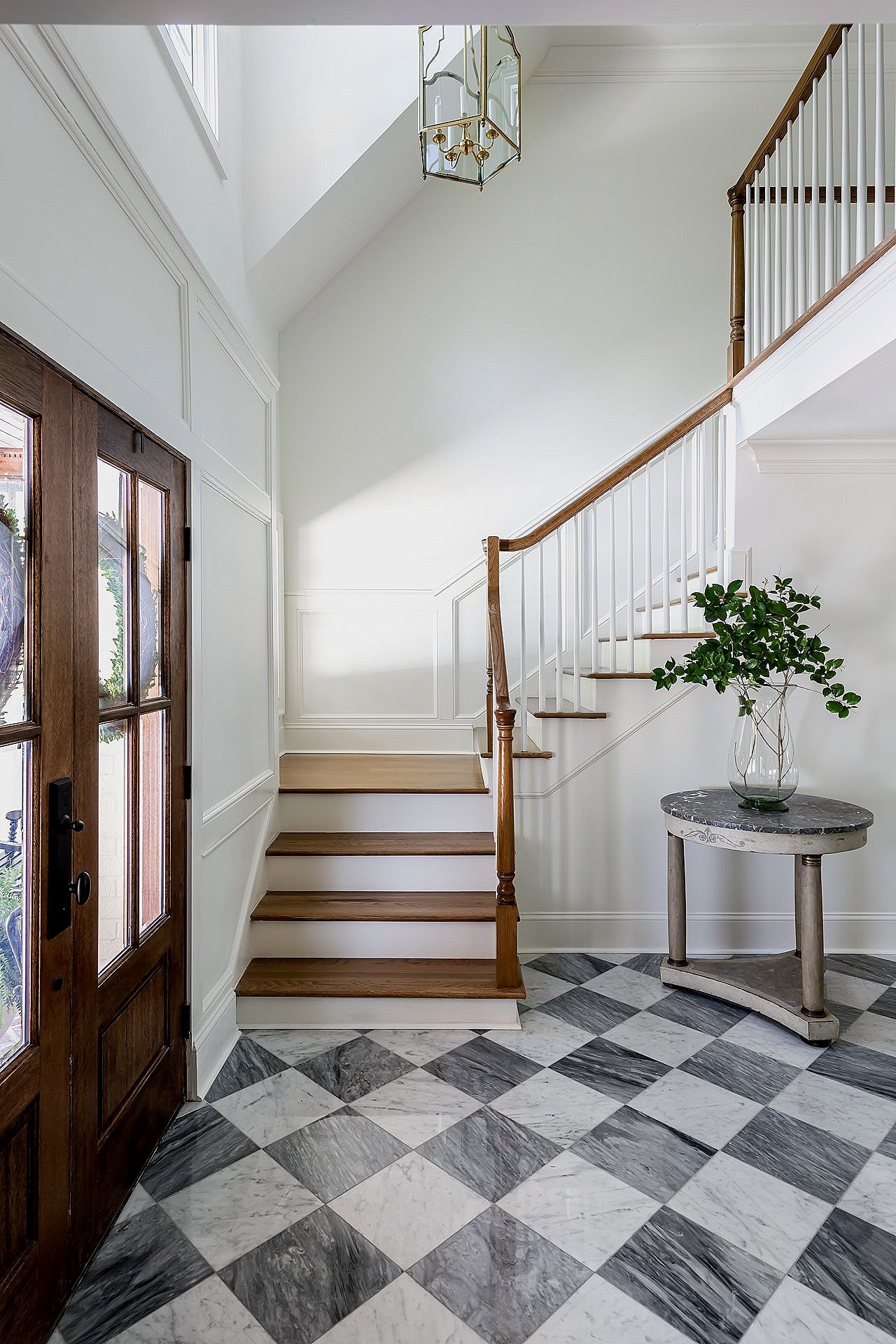 Double-height foyer at Project Lee Circle in Buckhead: custom wrought-iron staircase, white-oak herringbone floors, and a cascading crystal chandelier by Bradford Custom Homes.