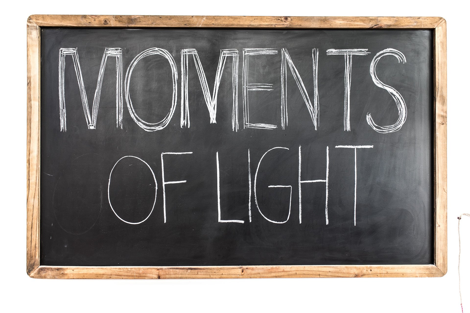Tafel mit der Aufschrift "MOMENTS OF LIGHT" in Kreide.