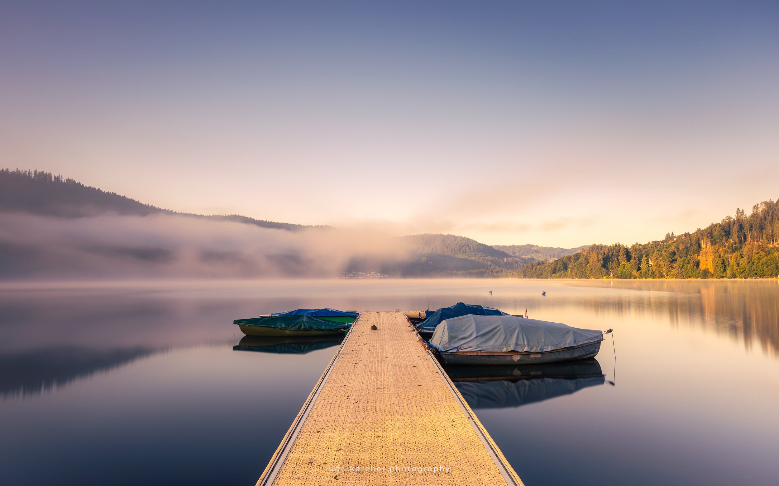 Peaceful Awakening – Die ersten Sonnenstrahlen über Titisee mit Bootsteg und leichtem Schleier von Bodennebel