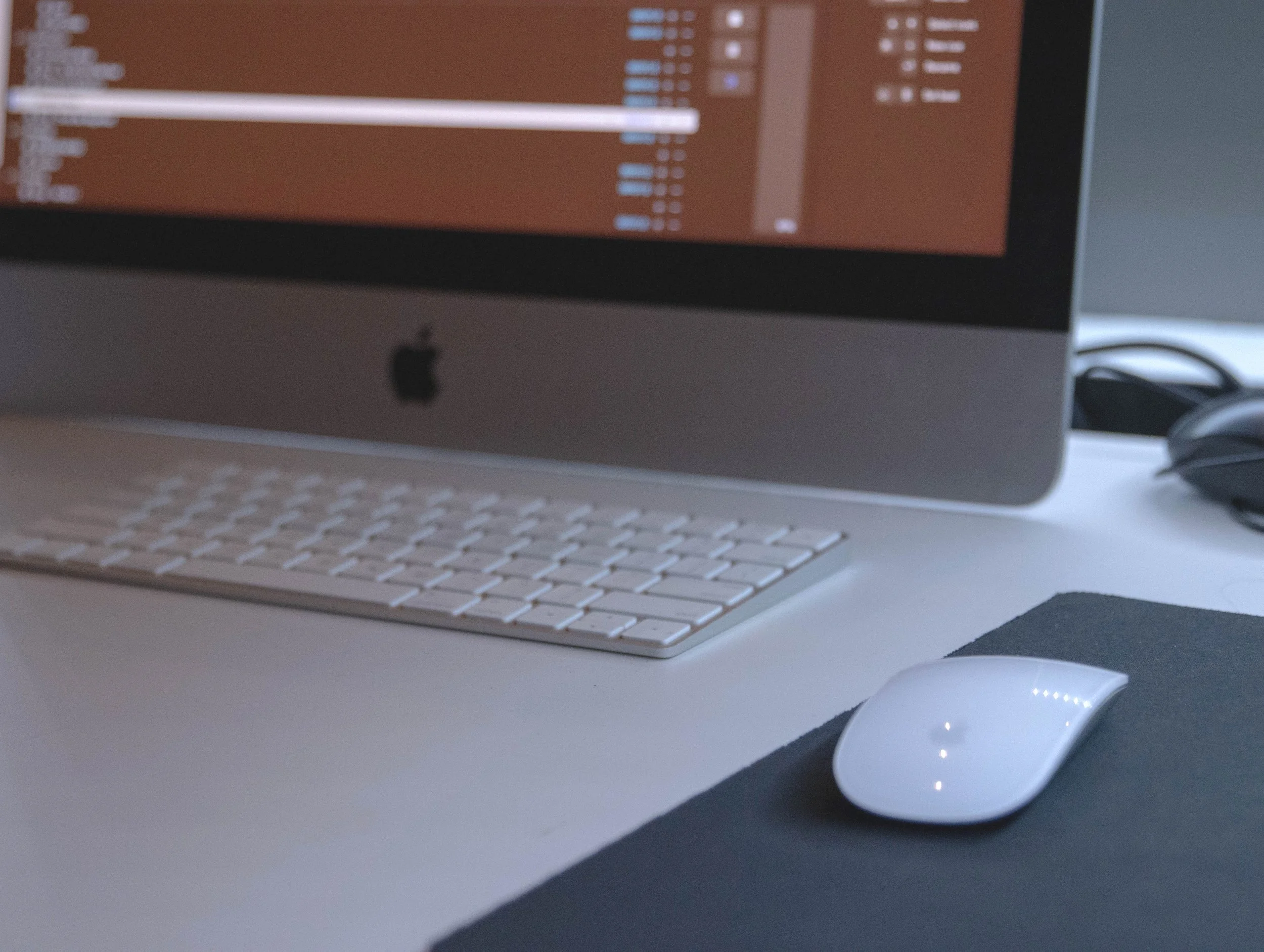 Computer workstation with monitor, Apple keyboard and mouse.