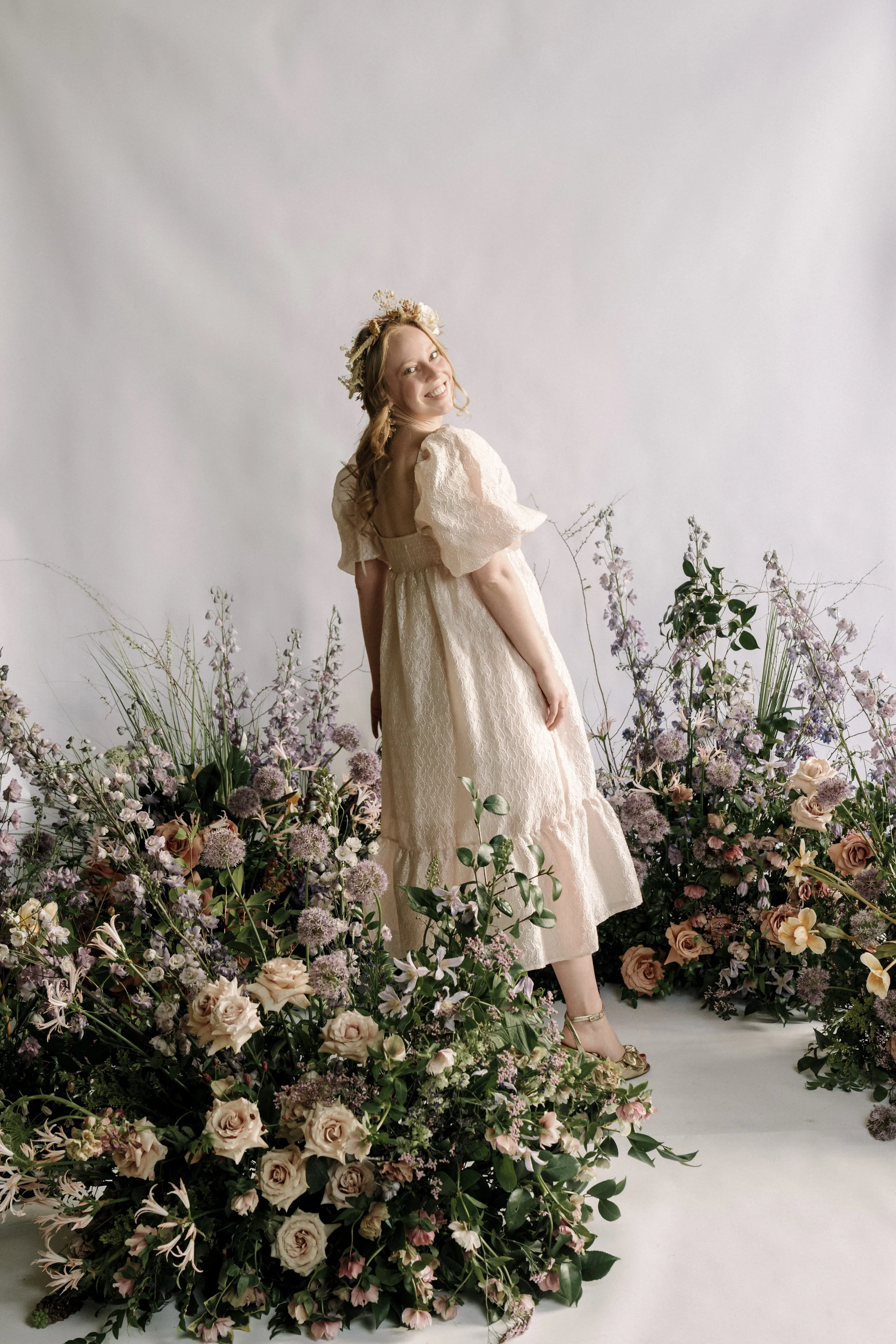 Photo of a woman standing in pink and purple flowers.