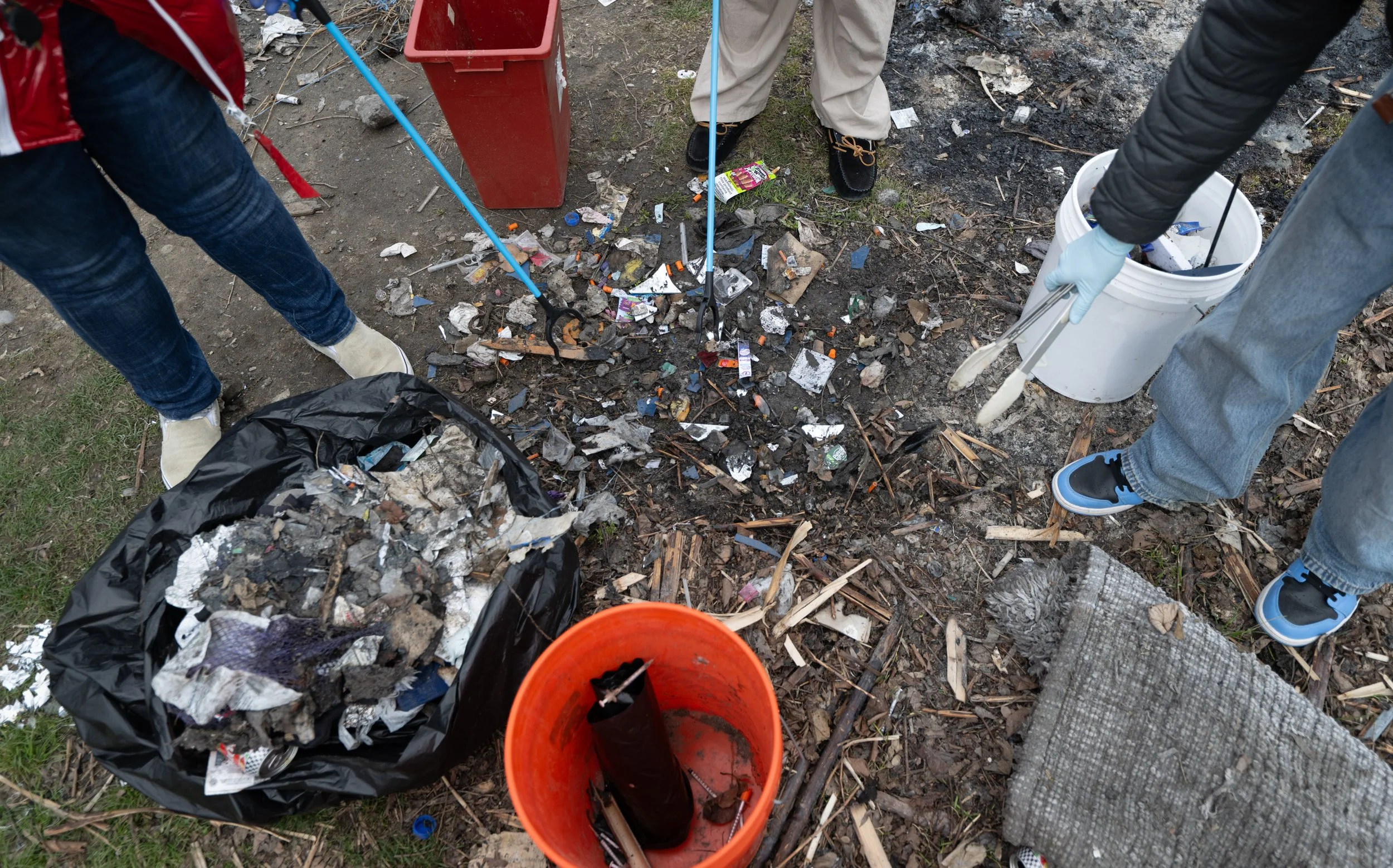 Khandi Perez, left, Izabella Forrester, middle, and Desmund Burns, right, pick up needles and garbage behind RAW on April 12, 2026.