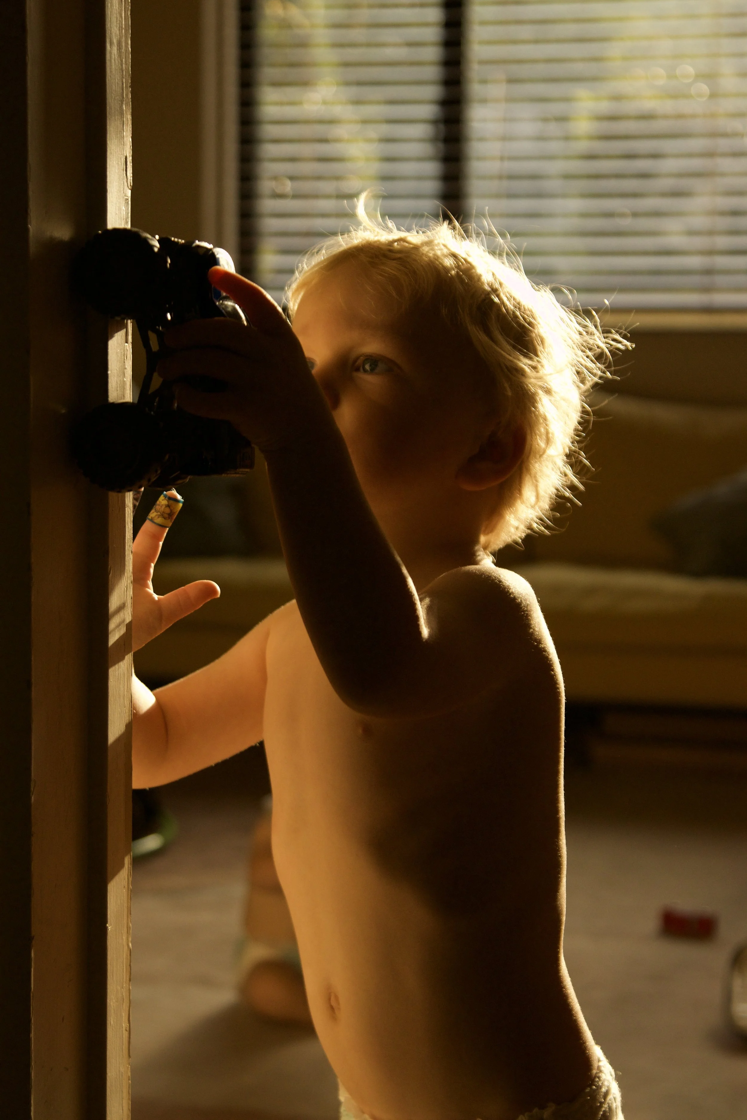 photograph of child playing at home with monster truck in gold light