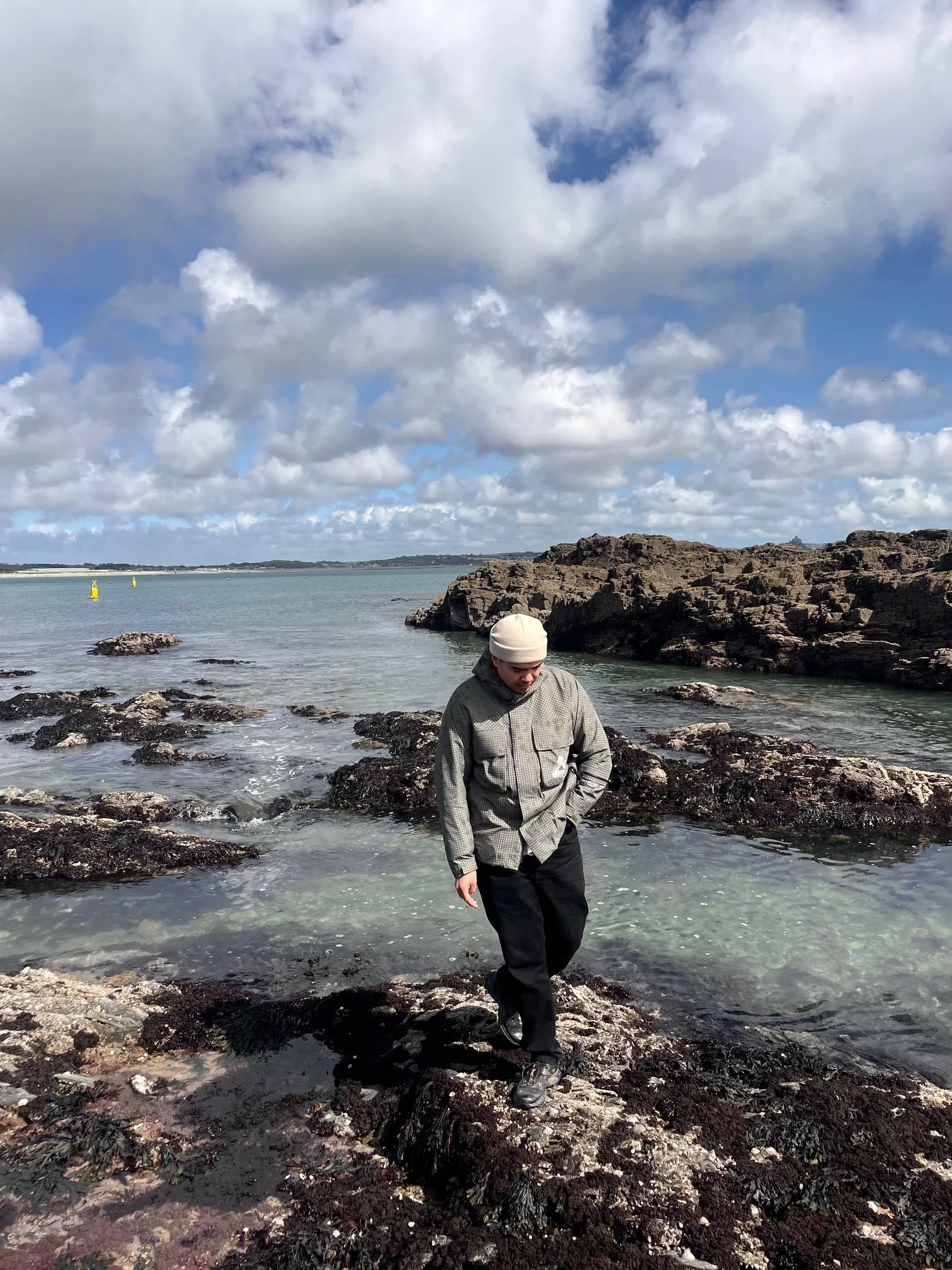 Man exploring rock pools with sea in the background