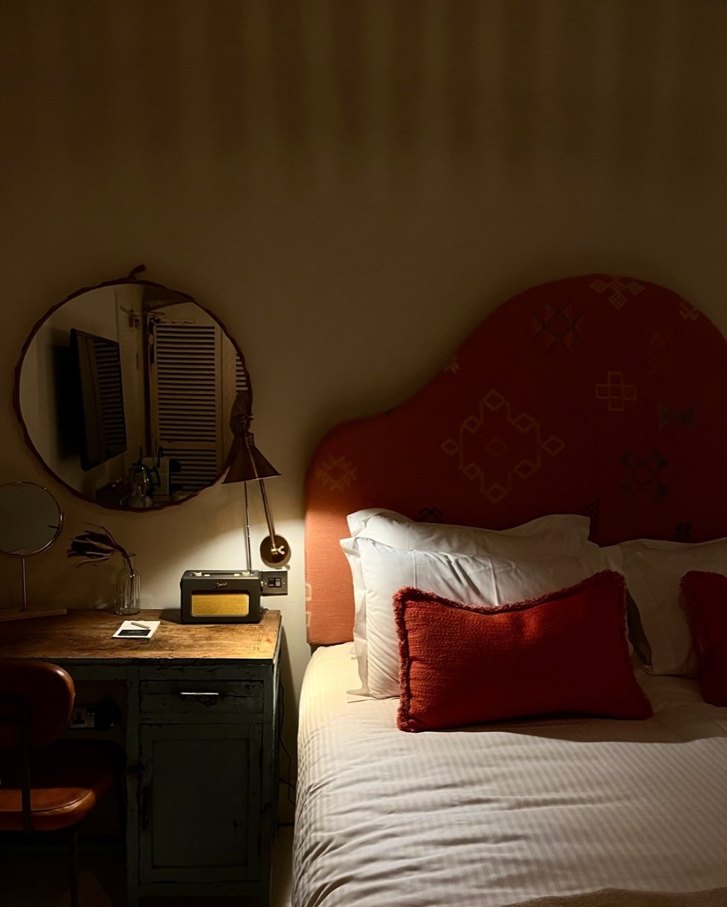 Dimly lit bedroom with large headboard and lamp