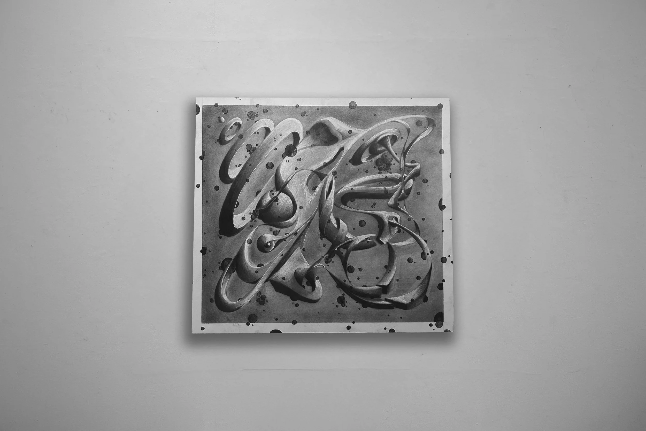Black and white abstract wall art with swirling, fluid shapes and scattered dots, mounted on a plain light-colored wall.