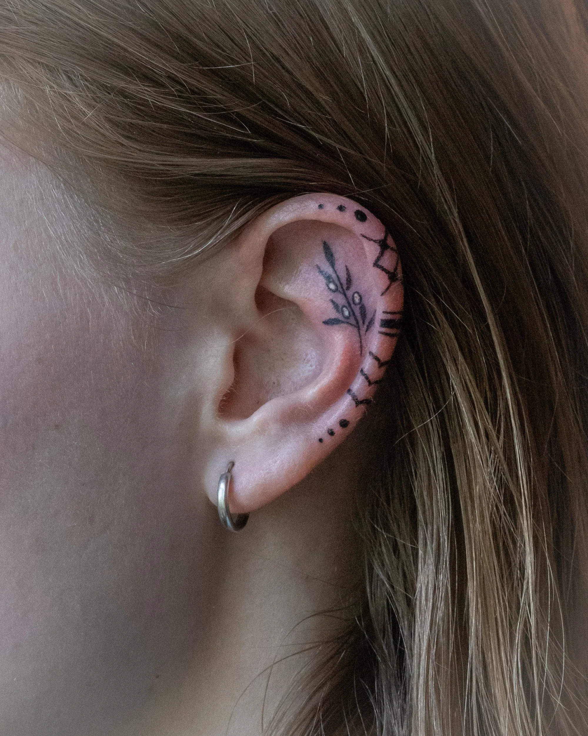 Ear ornament tattoo by Toronto tattoo artist Alexandria Rising, created in solidarity with Palestine. Inspired by the Keffiyeh, it features bold stripes, fishnet patterns, and curving lines symbolizing heritage, resilience, and connection.