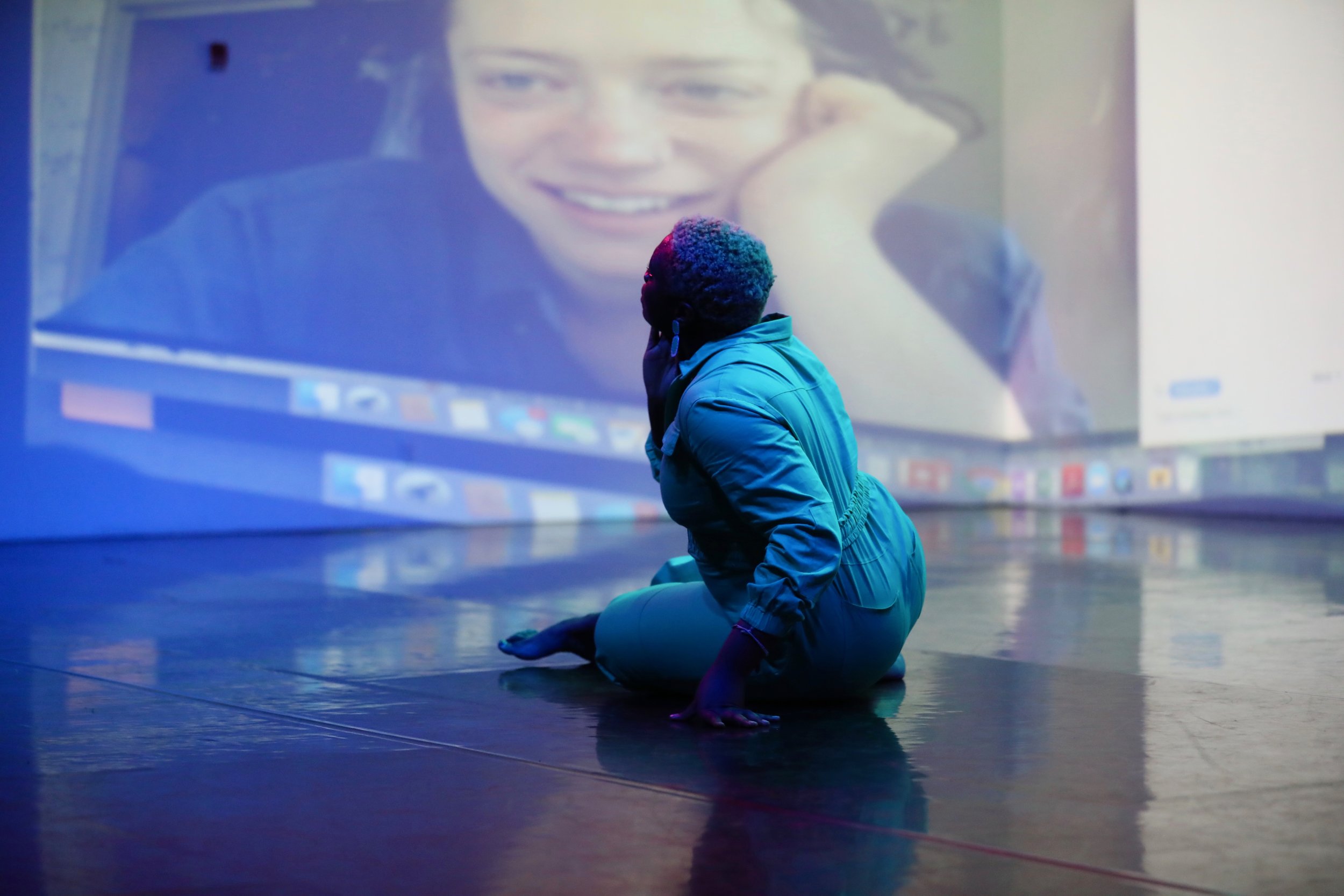 Ogemdi looks at projections behind her.