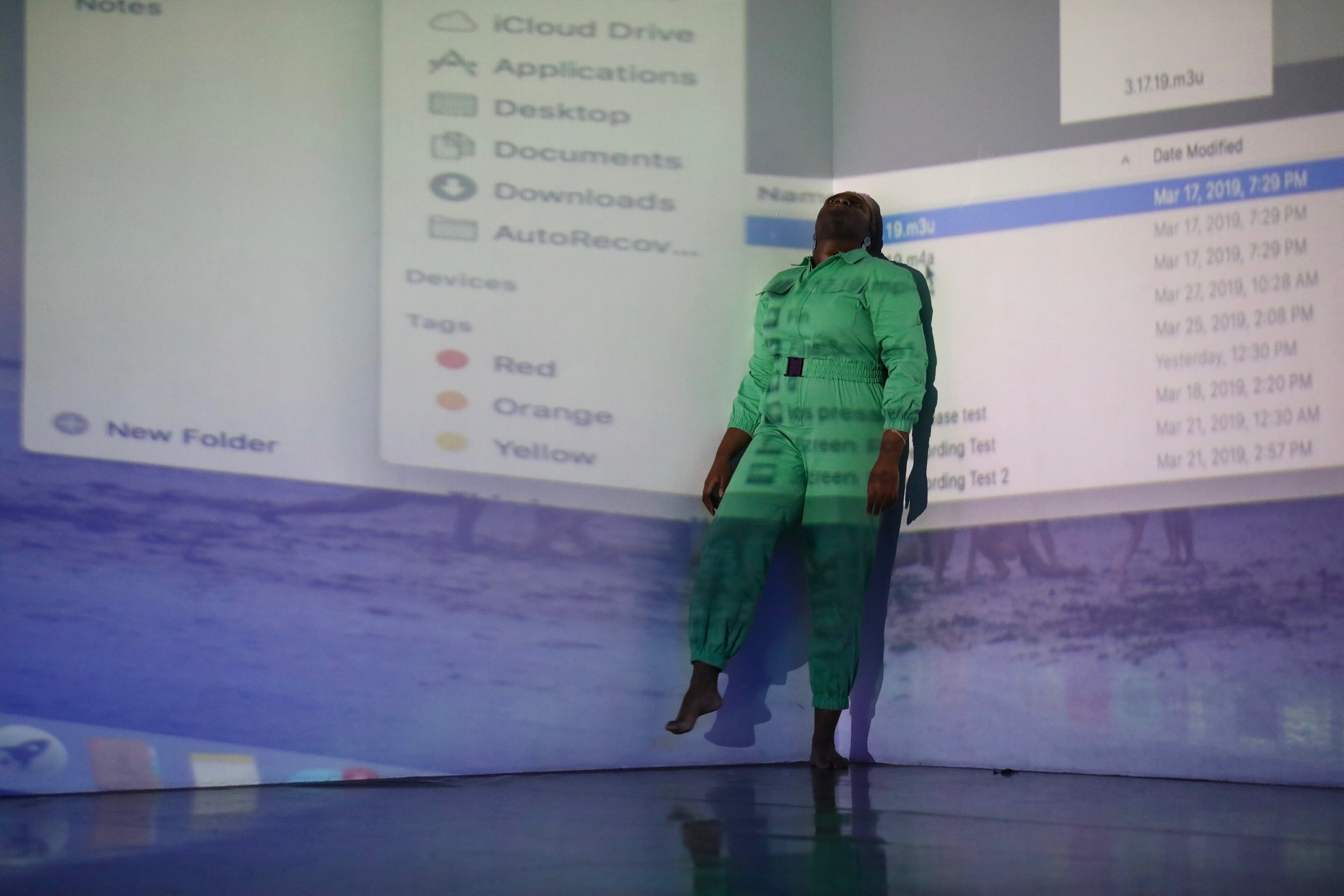 Ogemdi stands against a wall wearing a green jumpsuit.