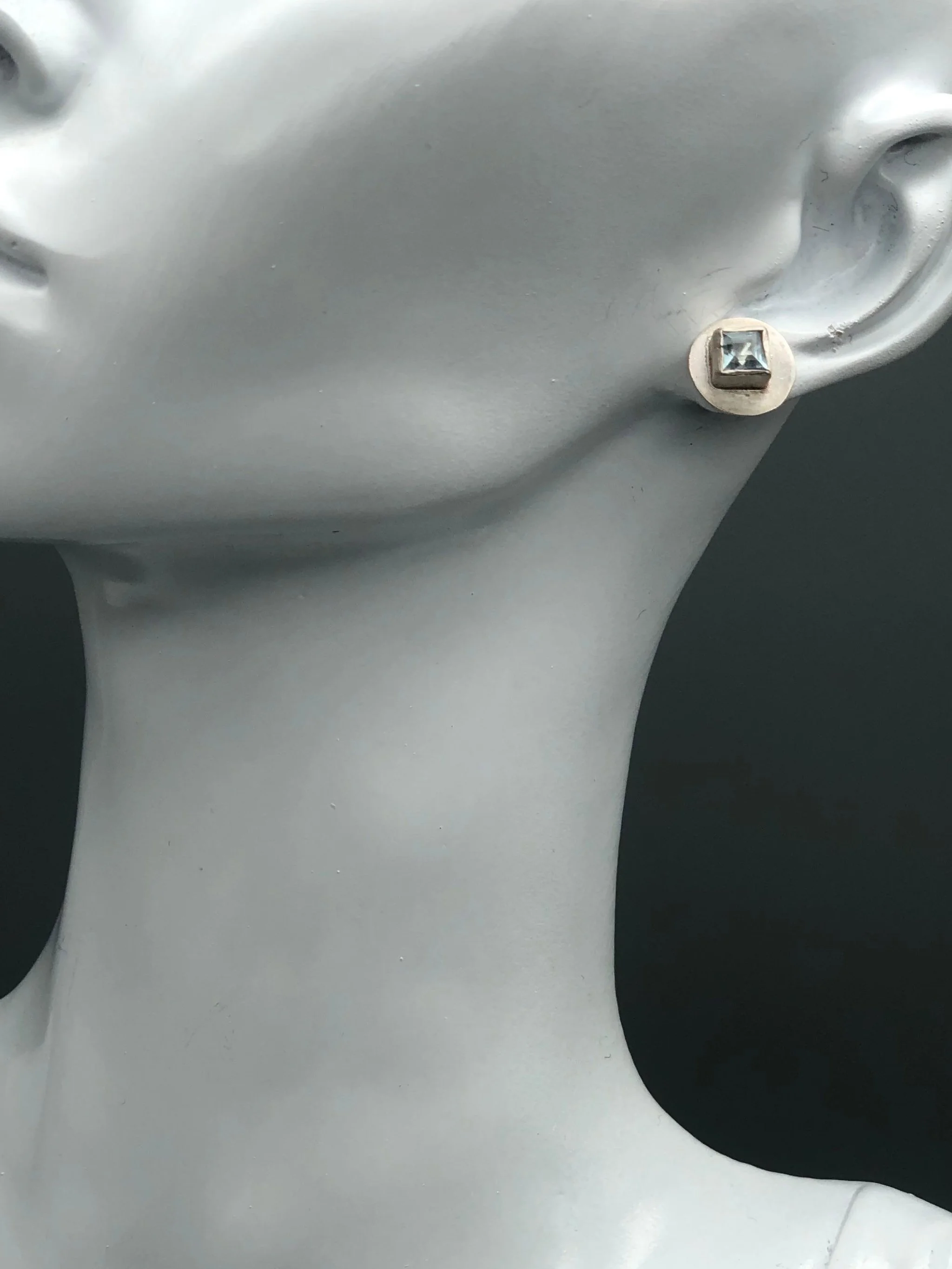 Vista indossata degli orecchini Monologue in argento satinato con acquamarina quadrata.
Worn view of the Monologue satin silver earrings with square aquamarine.