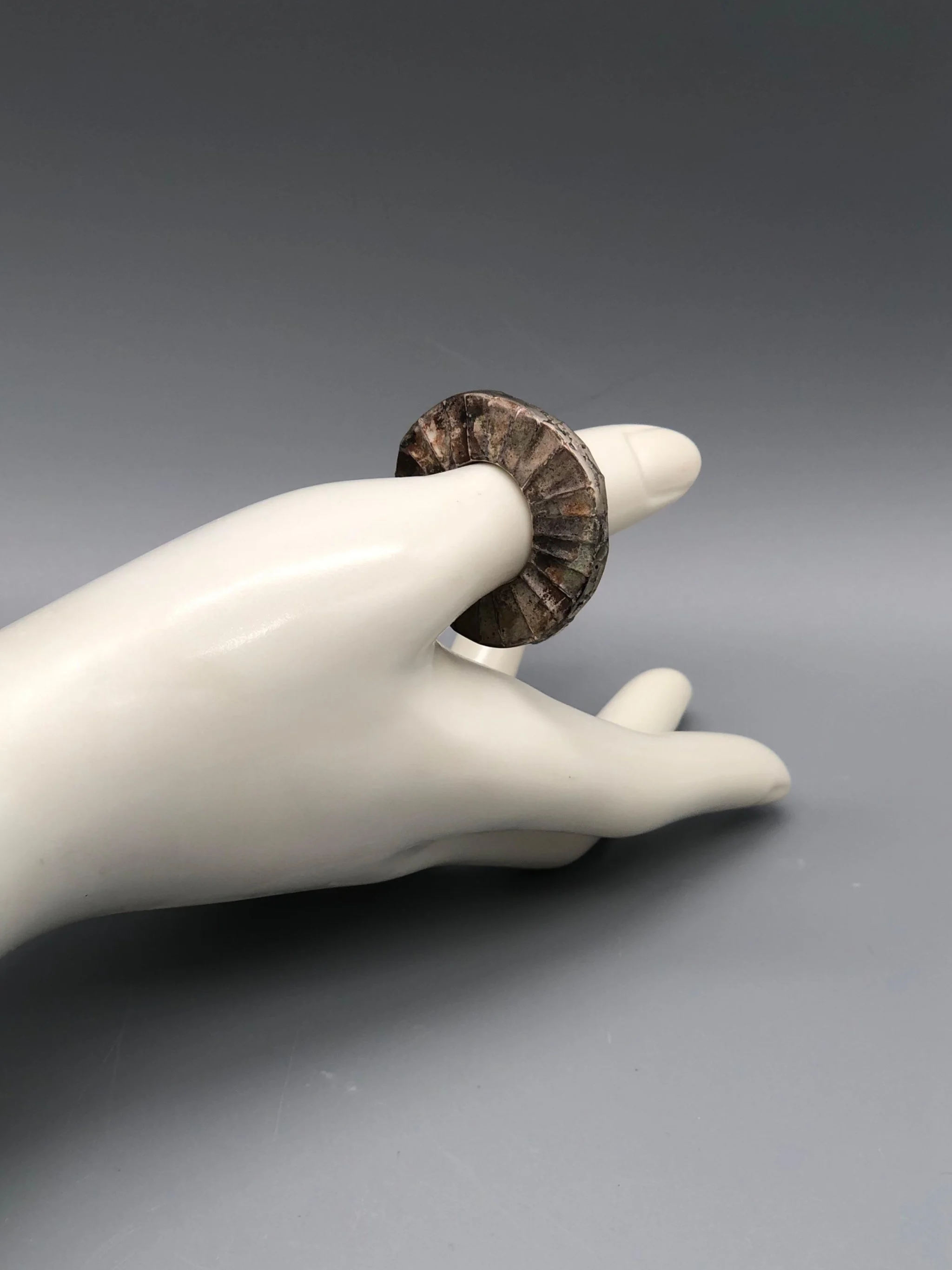 Mangàni Sole ring in oxidized 925 sterling silver with irregular circular form and radial textured surface.