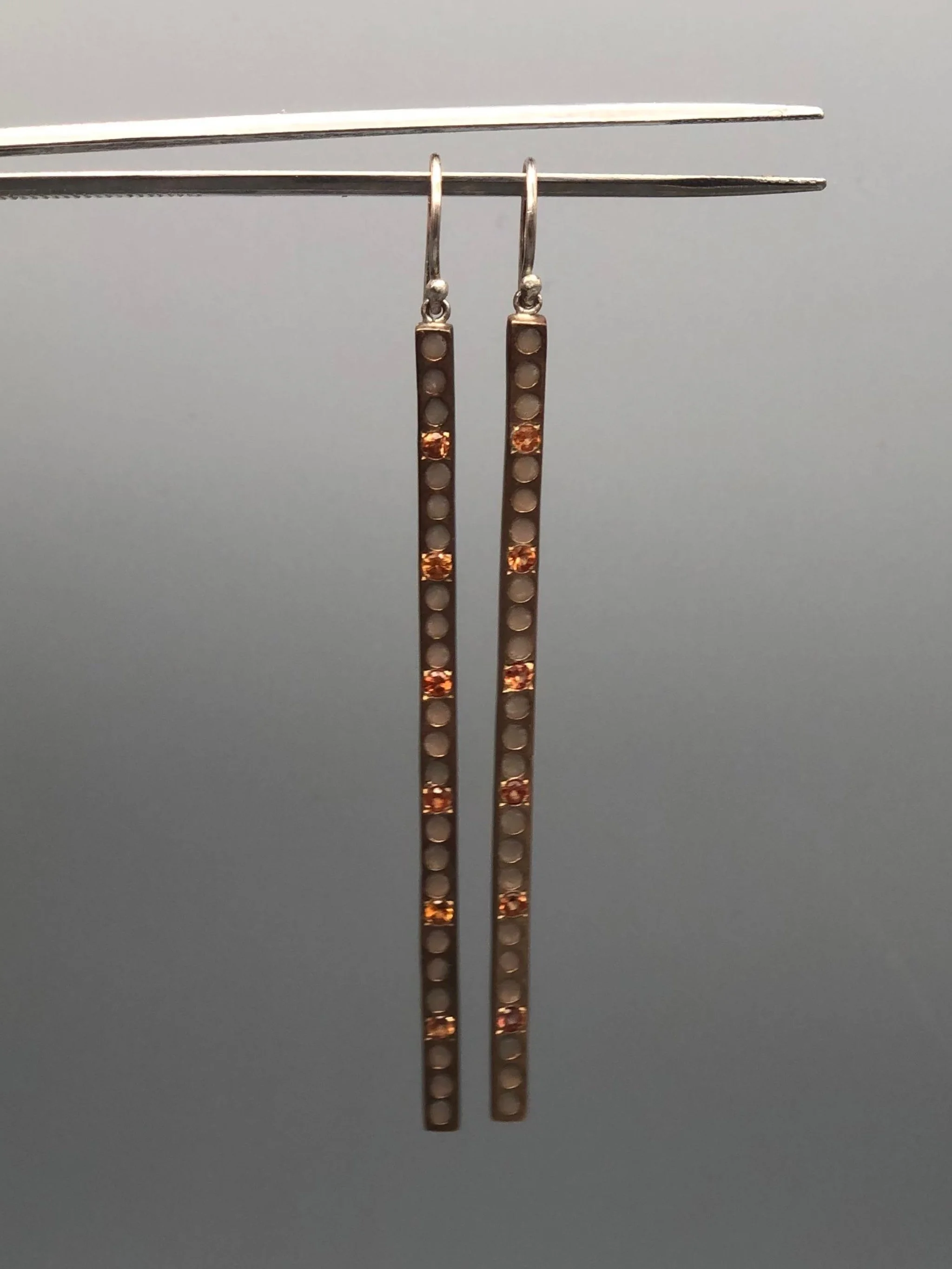 Orecchini lunghi in argento brunito ossidato con zaffiri arancio e smalto, design lineare a barra traforata, Riccardo Raimondi per Crepundia Gioielli Bologna