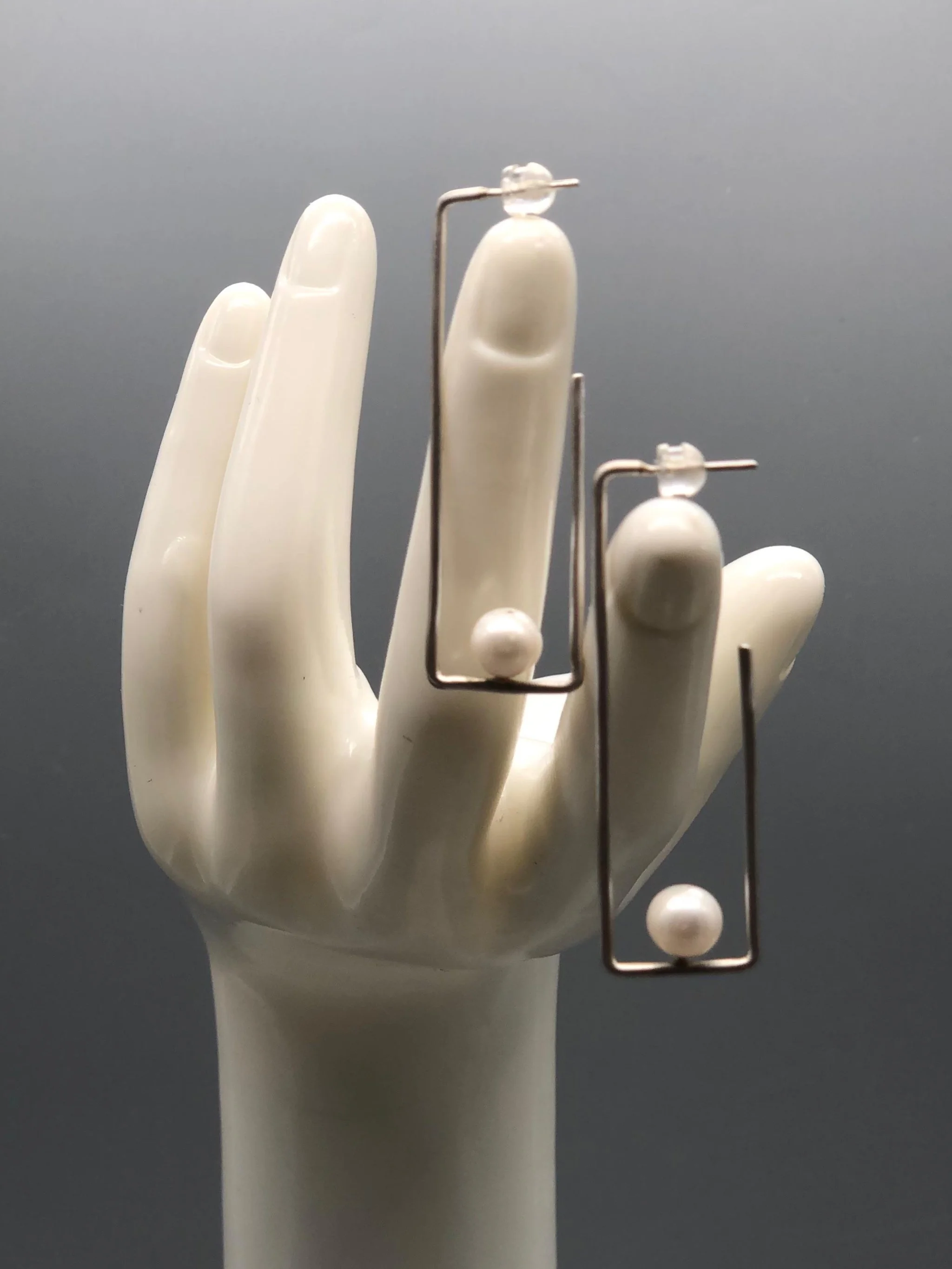 Crepundia Agadir earrings in silver with pearls, featuring an open, asymmetrical geometric design.