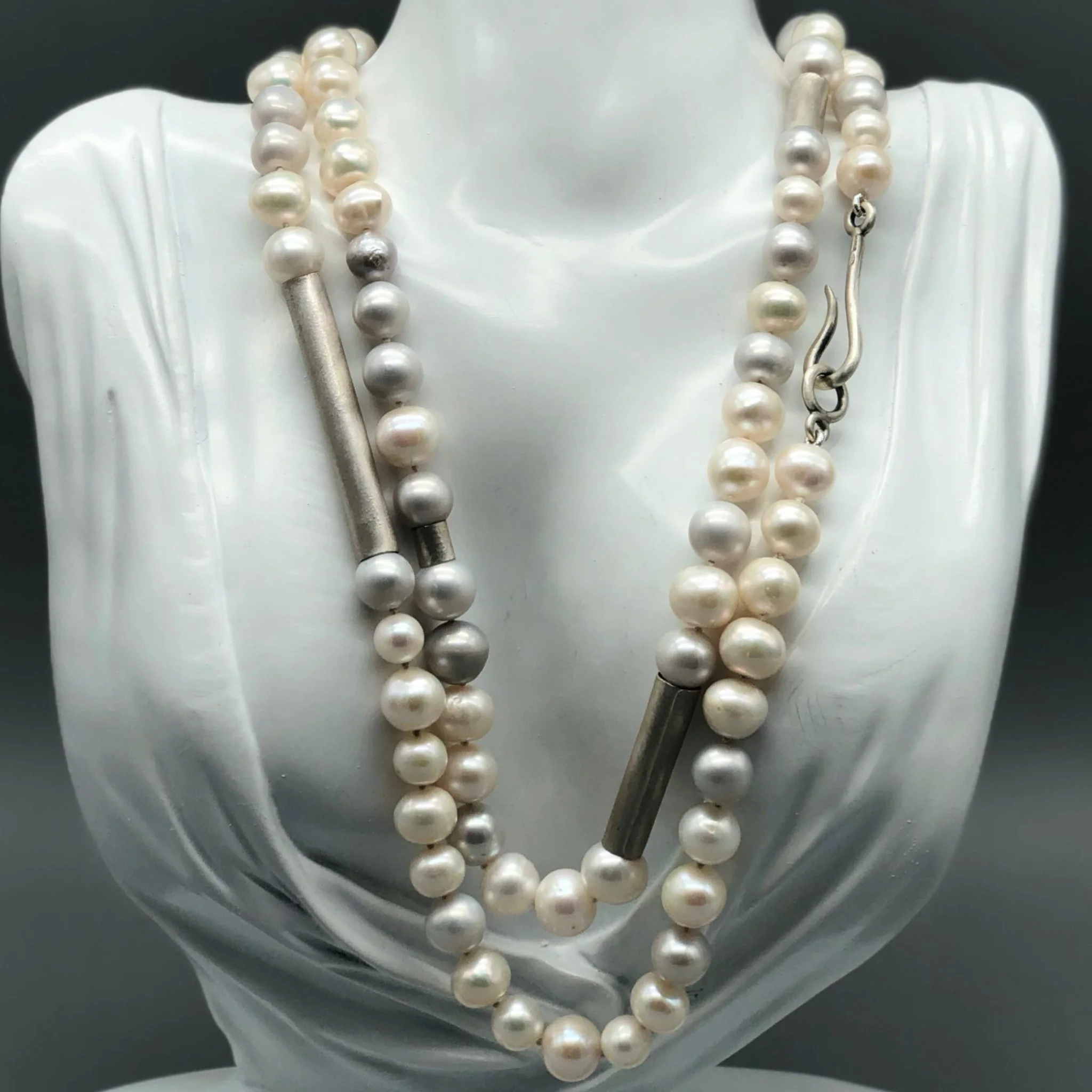 Collana di perle bianche e grigie con elementi in argento opaco, composizione fluida e modulare.
Crepundia Gioielli — Crepundia Bologna.
White and grey pearl necklace with matte silver elements, fluid and modular composition.
Crepundia Jewelry — Crep