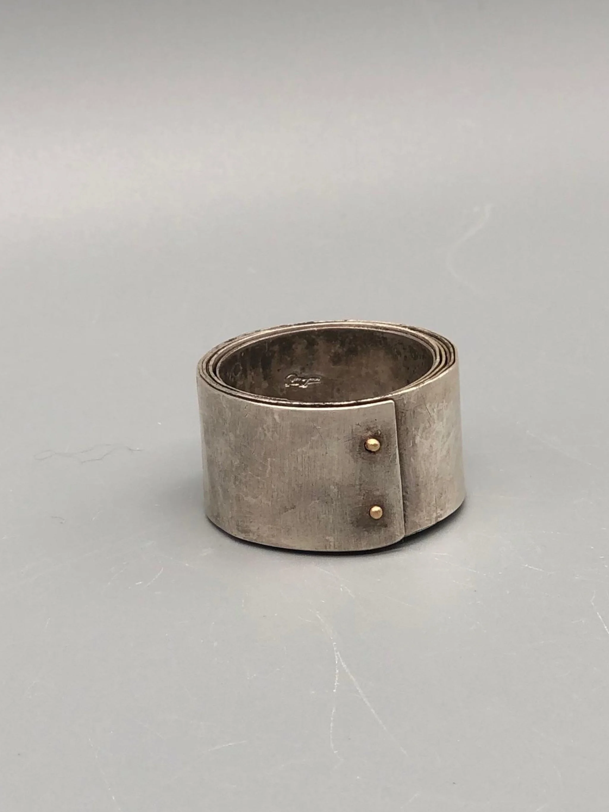 Girella ring by Mangàni in silver, featuring a wide coiled band accented with two small gold nails.