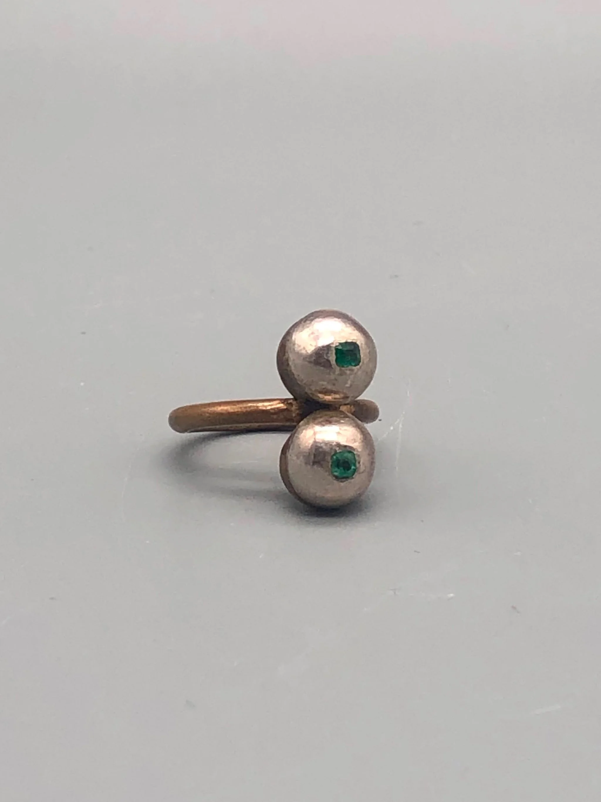 Raimondi ring in bronze and silver with two spherical elements and emeralds.