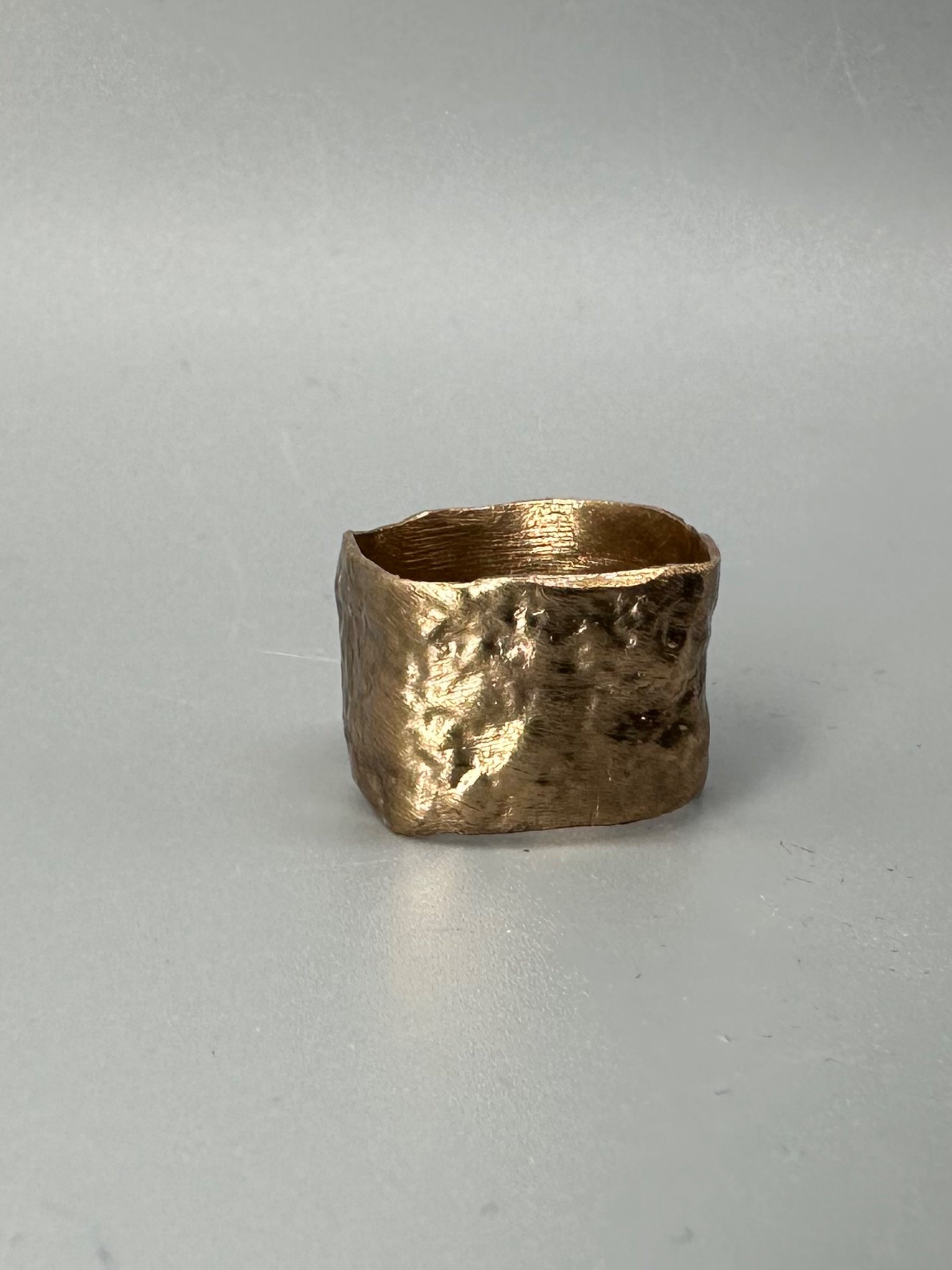 Anello Fascia Longobarda di CōDICEDS in bronzo bocciardato, dalla forma ampia e irregolare.  Longobarda wide bronze ring by CōDICEDS, with a hammered surface and irregular shape.