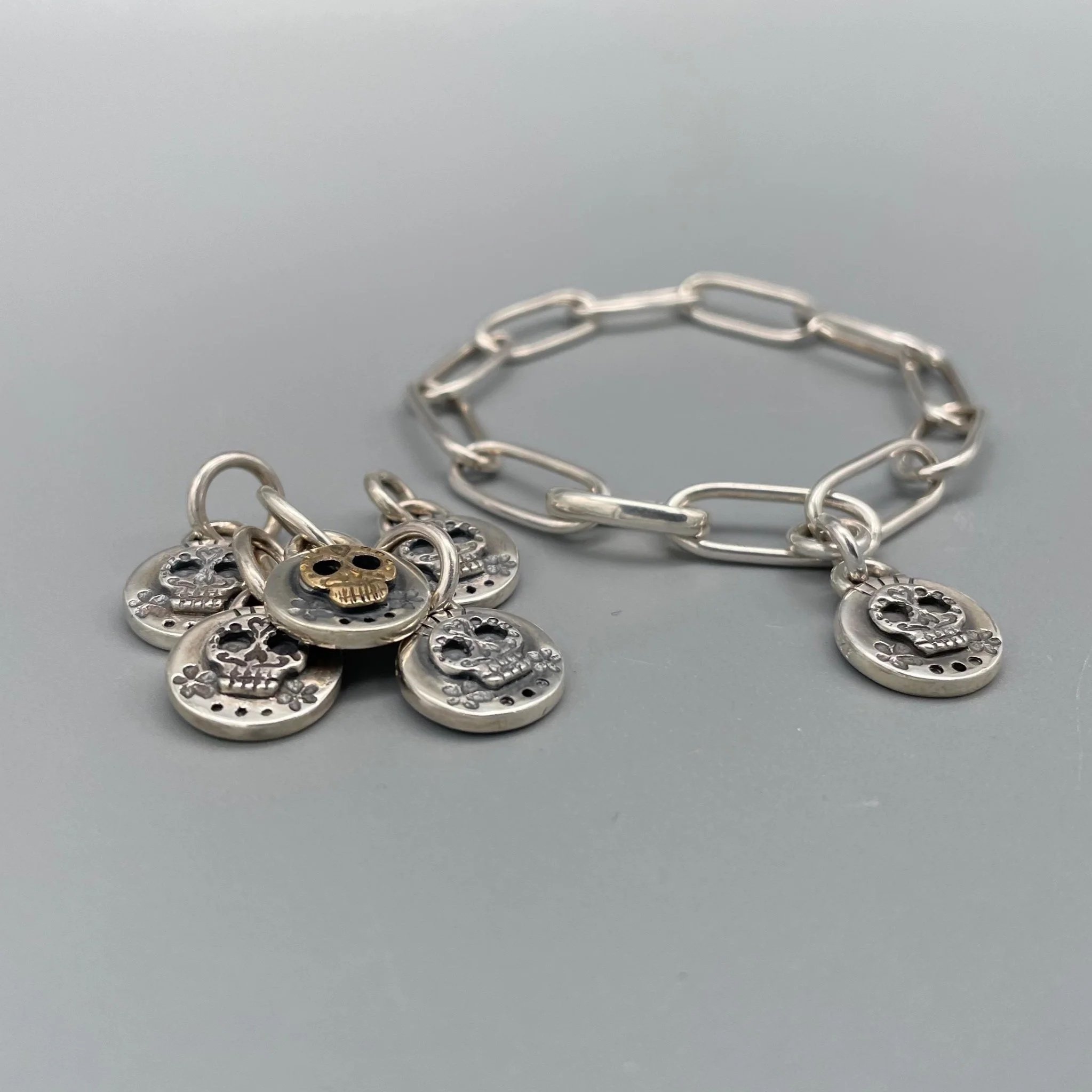Bracciale e ciondoli in argento con dettagli in oro, segni simbolici che definiscono un linguaggio identitario.
Silver bracelet and charms in silver with gold details, symbolic signs defining an identity language.
Crepundia Gioielli — Crepundia Bolog