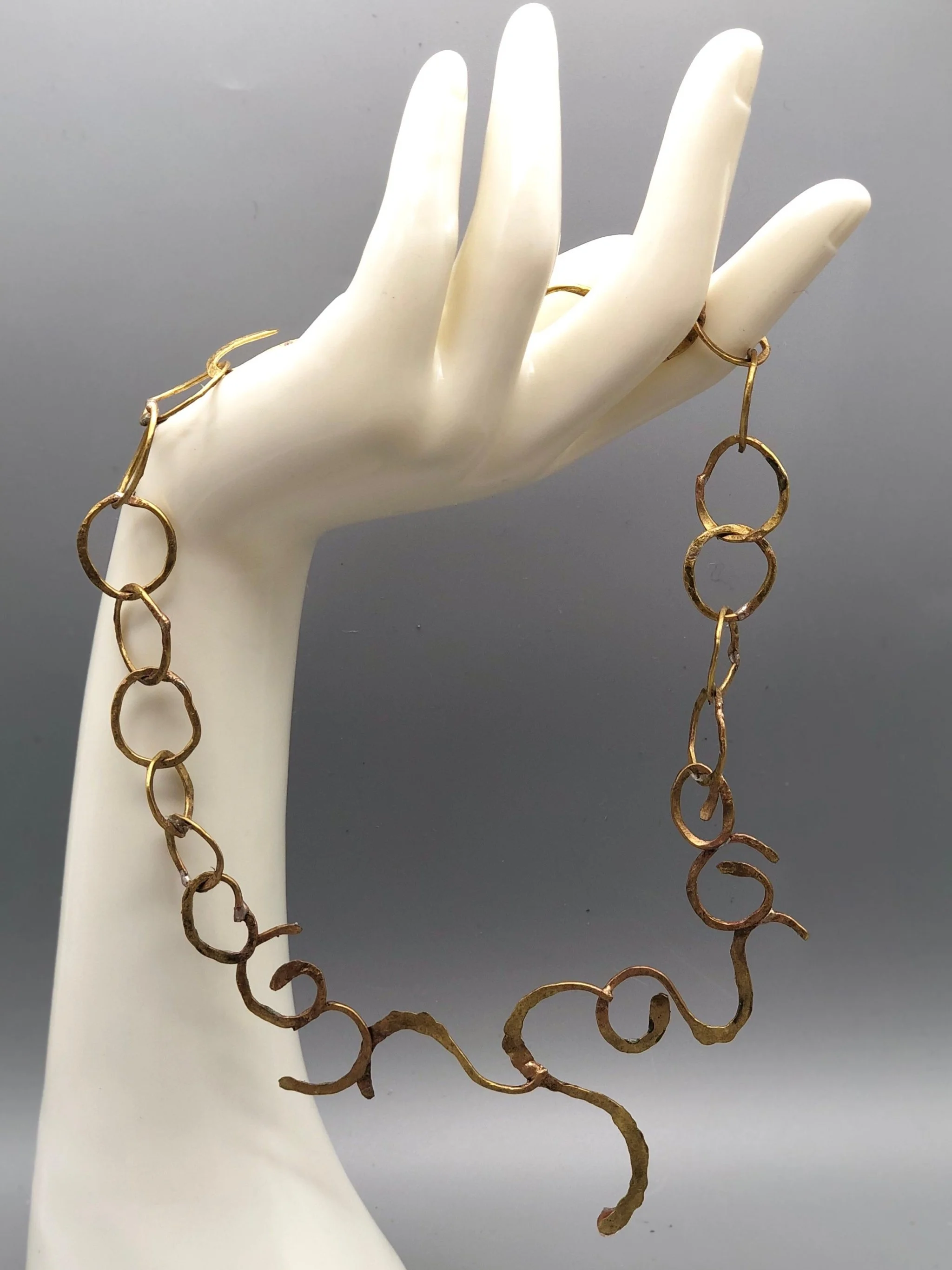Collana Free Line di Claudia Cuzzeri in ottone opaco, con anelli irregolari e elemento centrale scultoreo a linea libera.