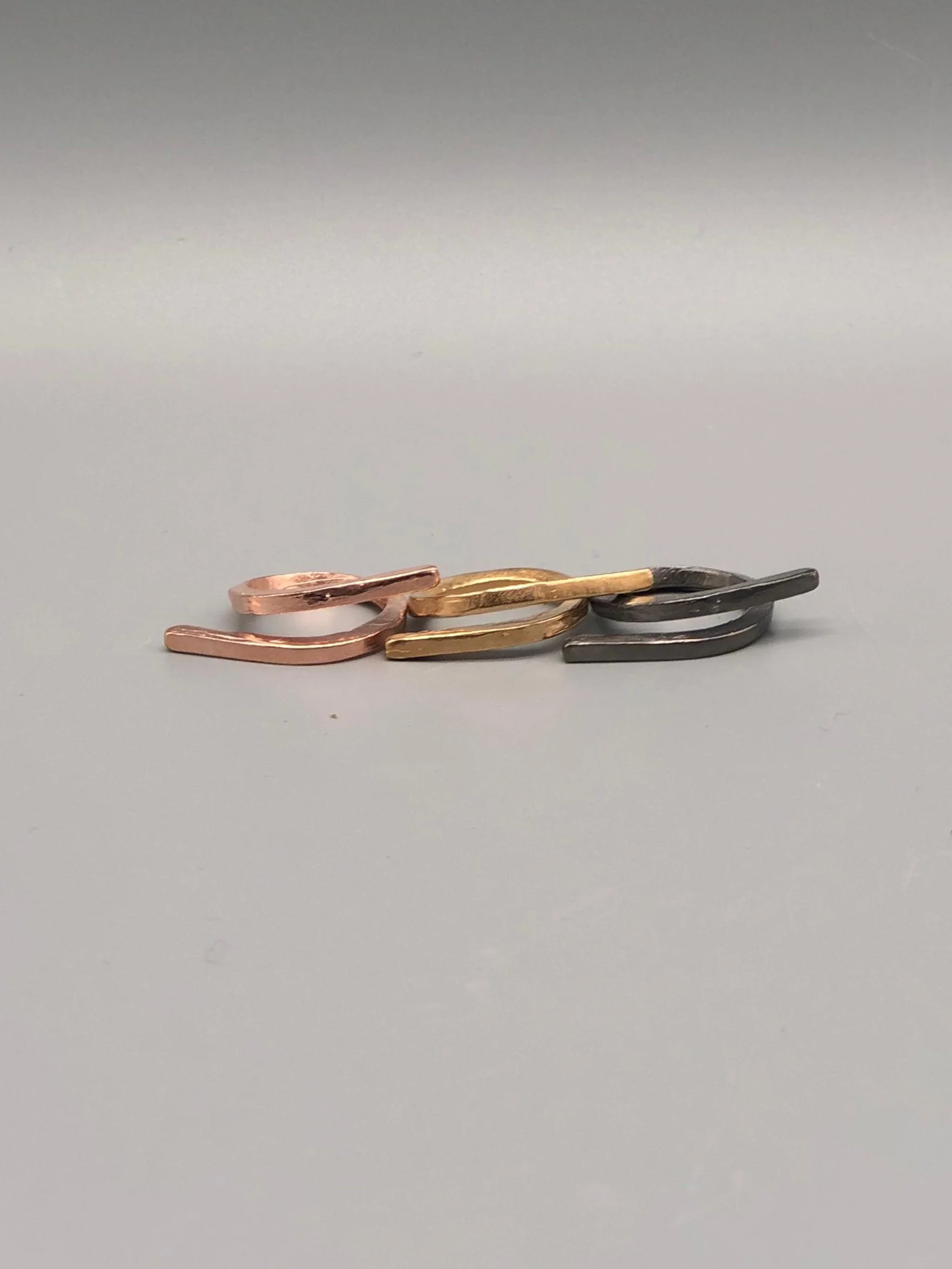 EL Gioielli Nodo ring in rose gilded bronze, yellow gilded bronze and ruthenium-plated bronze. Minimal contemporary open ring photographed at Crepundia Gioielli Bologna.
