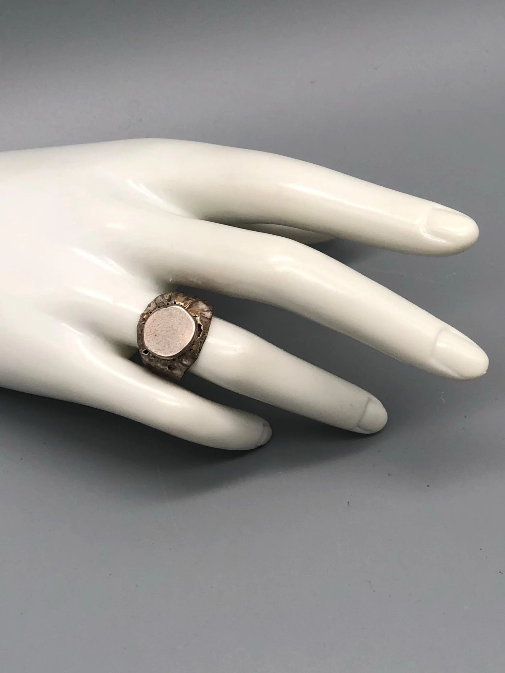 Marco Mangàni signet ring in sterling silver with irregular sculptural surface and flat central plate, Crepundia Gioielli Bologna
