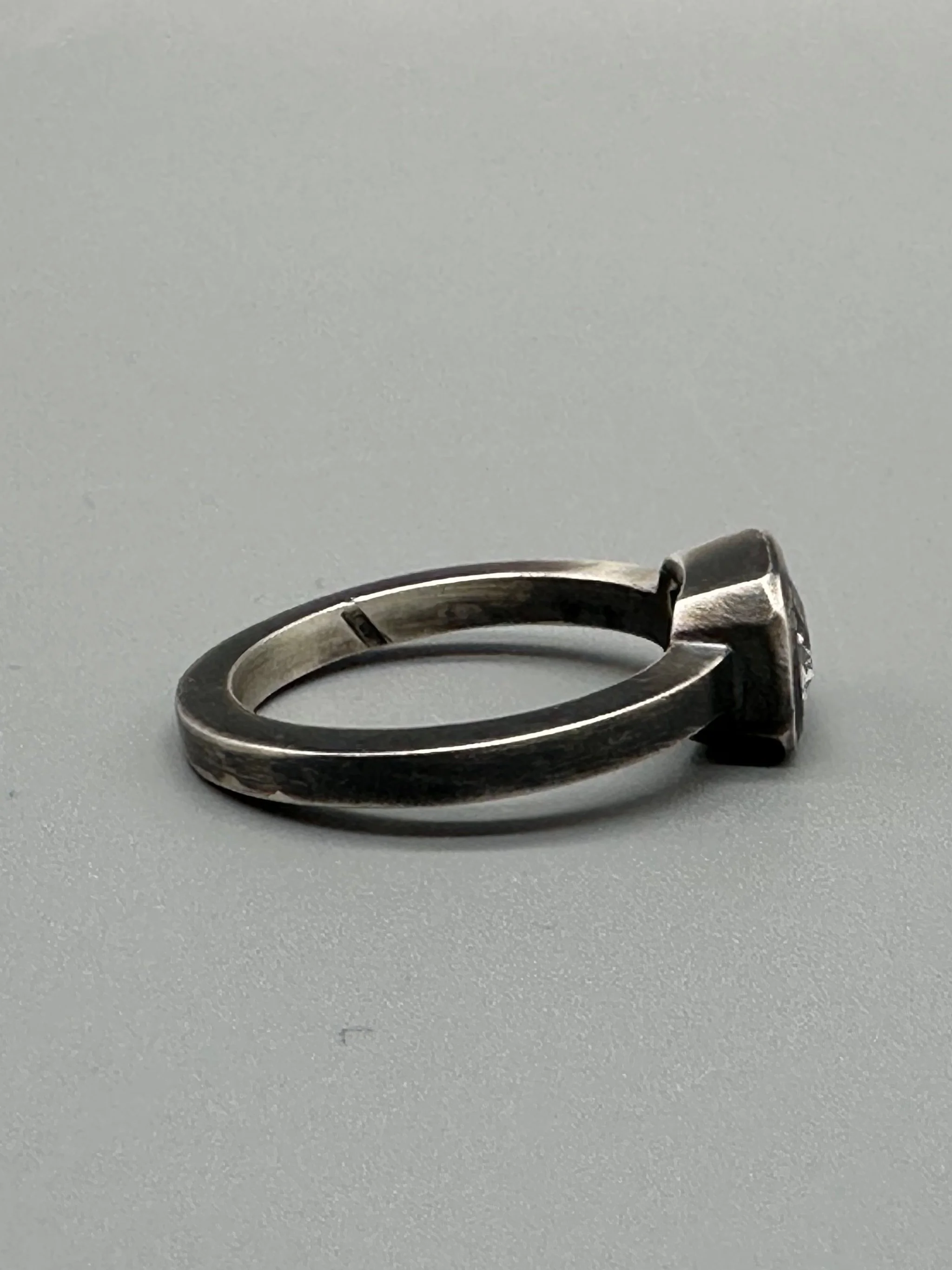 Anello White in Black in argento brunito con topazio bianco sfaccettato e castone geometrico. White in Black ring in oxidized sterling silver with faceted white topaz and geometric setting.