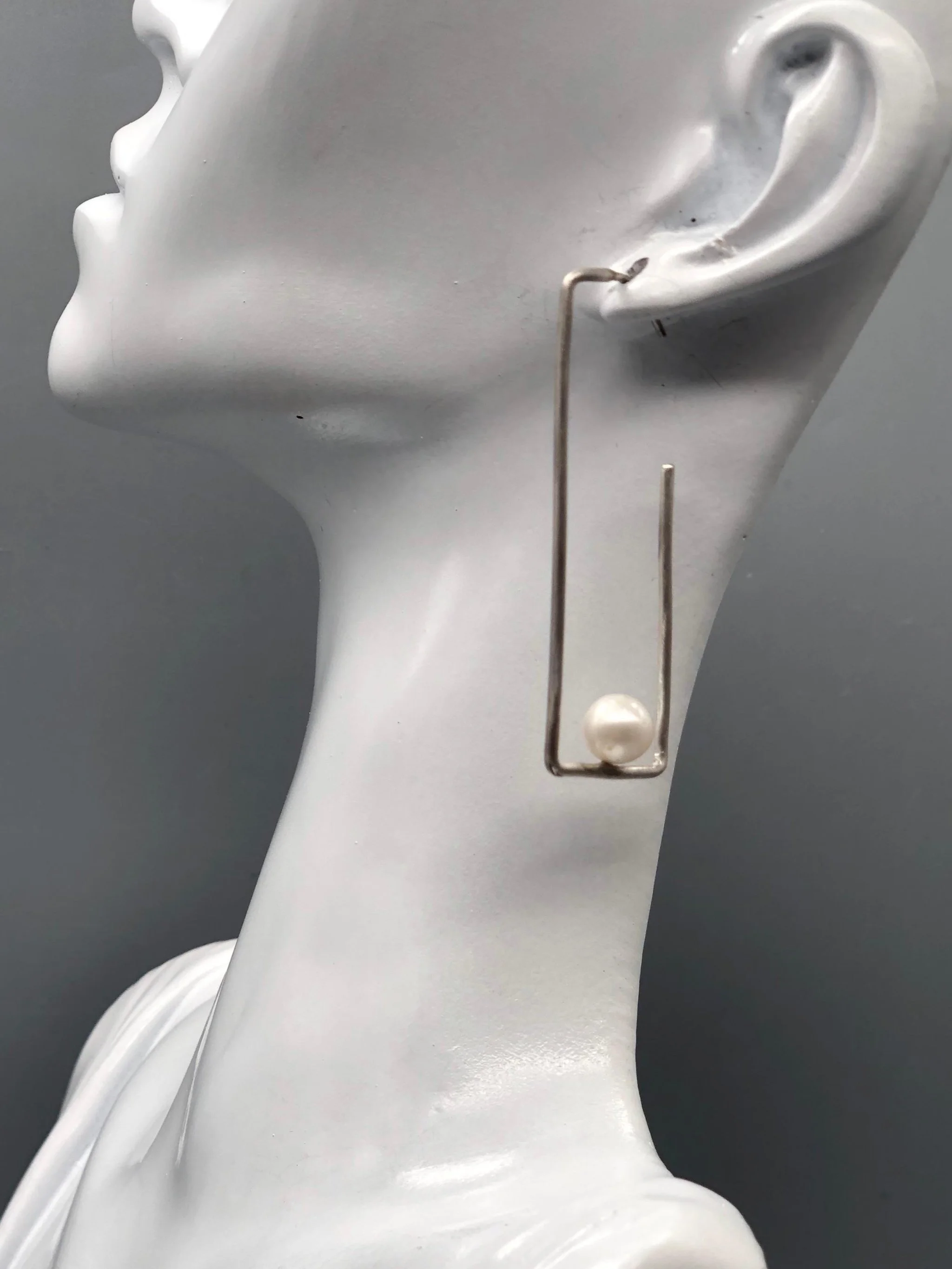 Crepundia Agadir earrings in silver with pearls, featuring an open, asymmetrical geometric design.