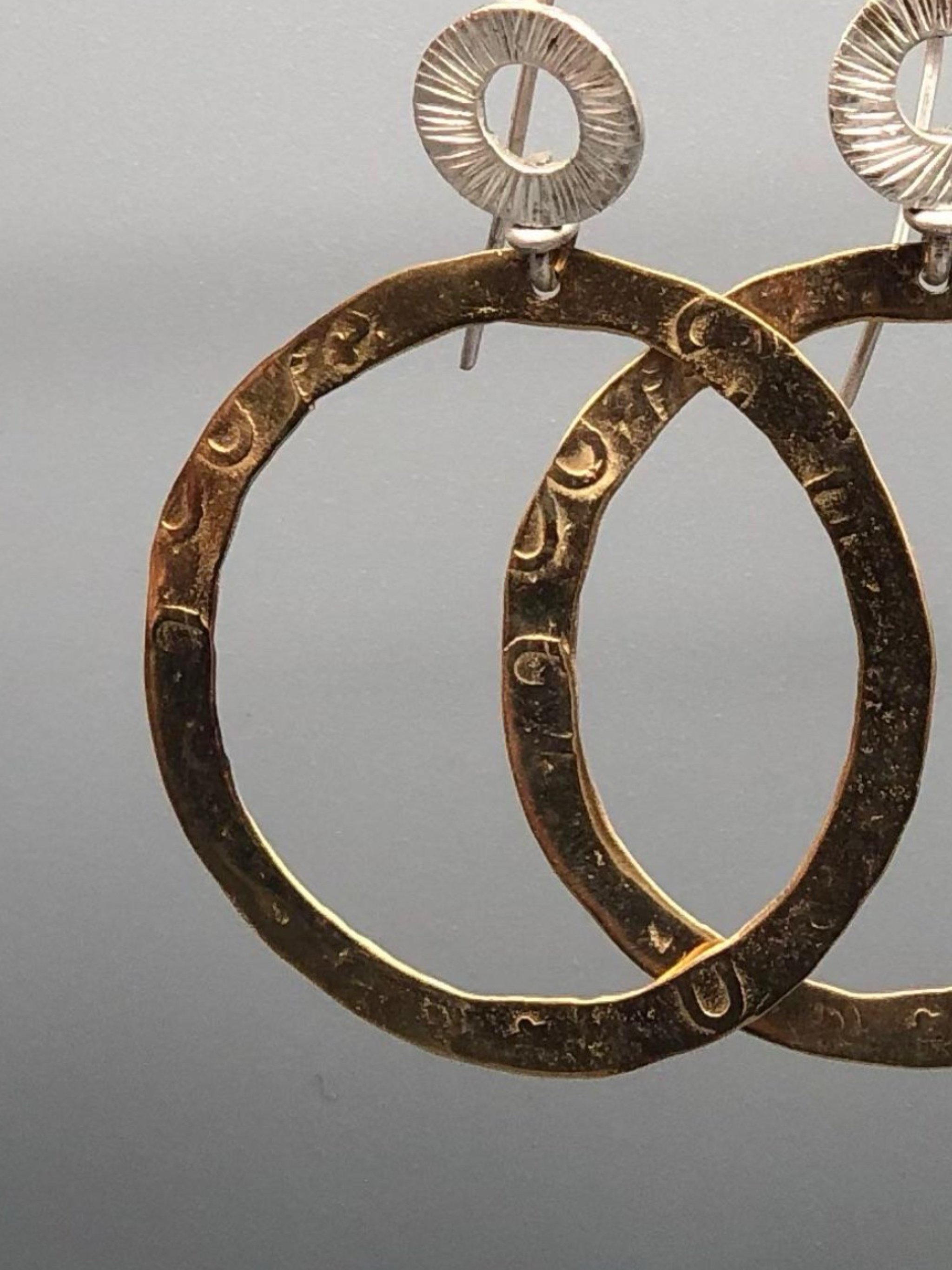 Dettaglio superficie incisa orecchini cerchio bronzo dorato e argento Gabriel Reinoso Crepundia Bologna