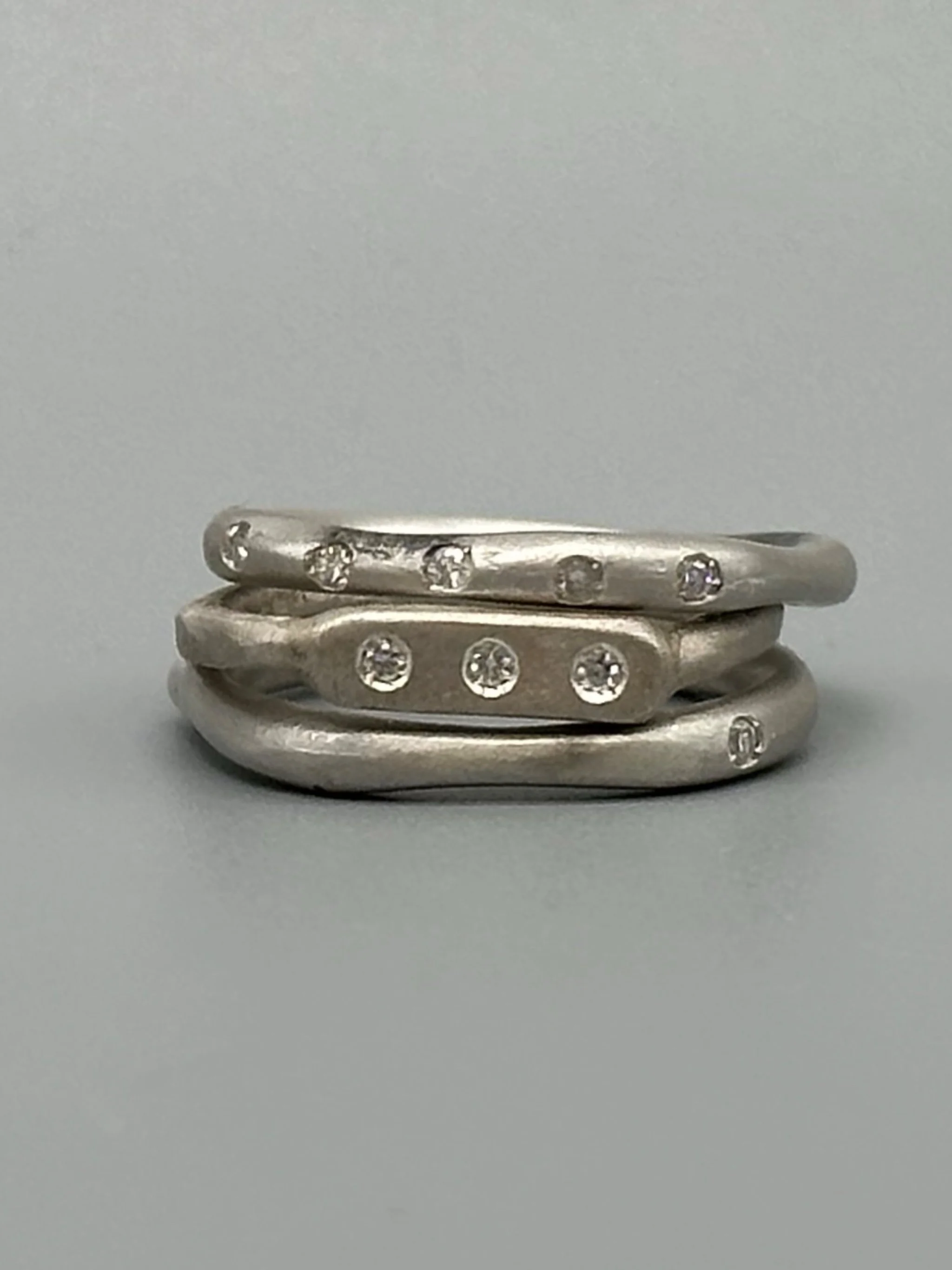 Interplay di Crepundia Gioielli, composizione di tre anelli in argento Full Wave, Wave e Flat 3, con diamanti per un totale di 0,12 ct. Interplay by Crepundia Gioielli, a set of three contemporary sil