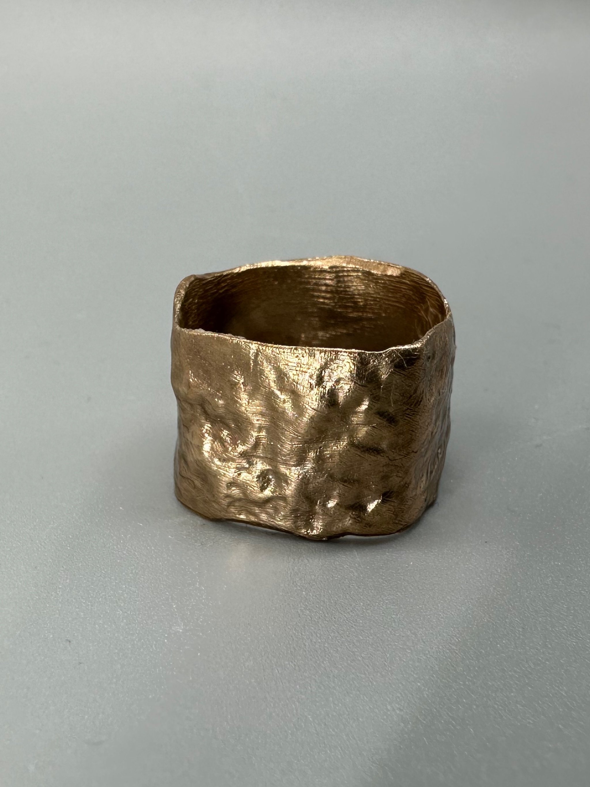Anello Fascia Longobarda di CōDICEDS in bronzo bocciardato, dalla forma ampia e irregolare.  Longobarda wide bronze ring by CōDICEDS, with a hammered surface and irregular shape.