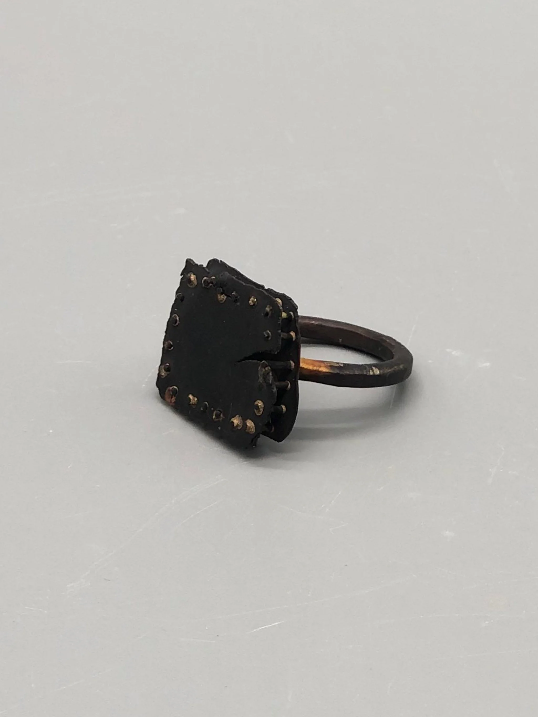 Anello Gabbia di Marco Mangàni in oro 14 kt e oro 18 kt ossidato, con struttura a sbarre e due diamanti grigi nascosti all’interno.