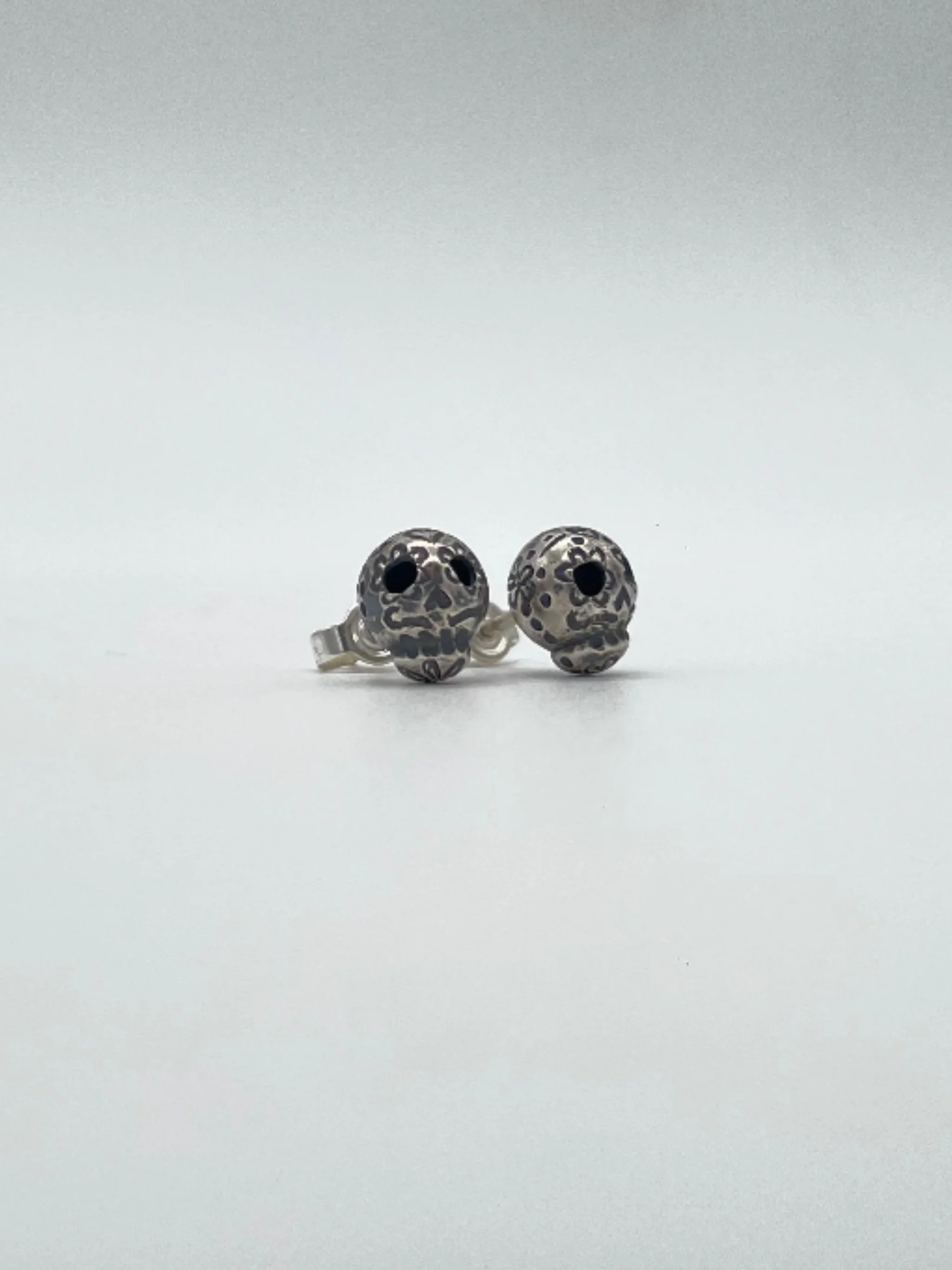 Sonja Markhoff Calavera de Dulce earrings in sterling silver, small engraved skull stud earrings, contemporary jewelry by Crepundia Gioielli Bologna