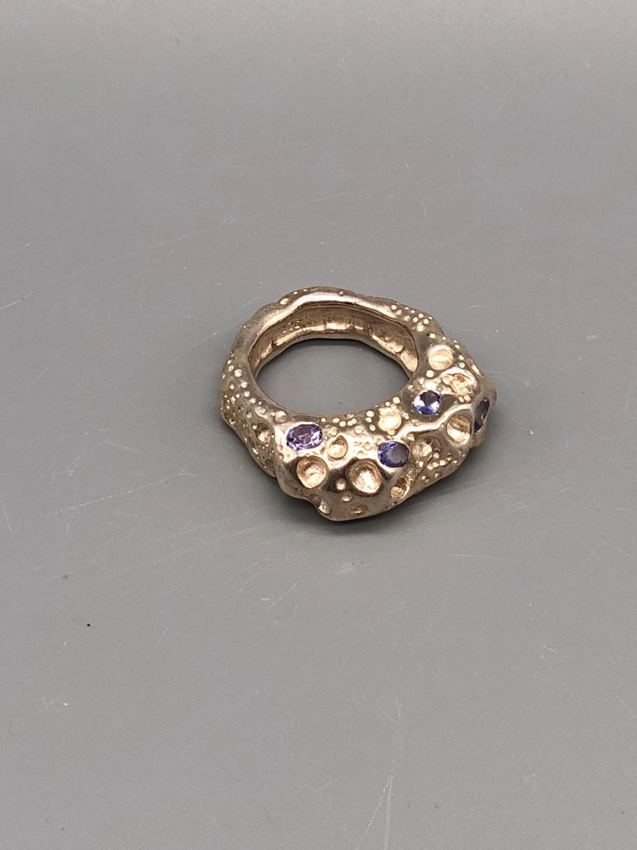Anello Luna di Portas in argento con quattro tanzaniti blu incastonate su una superficie lavorata con incisioni, cavità e rilievi.