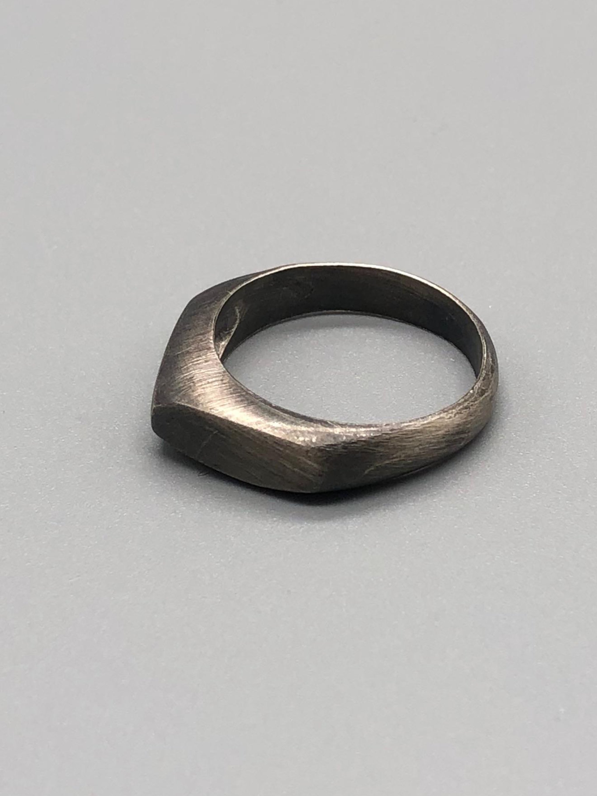 Anello Cuspide Crepundia in argento 925 brunito, con fascia geometrica, superfici sfaccettate e finitura scura satinata\.  *Crepundia Cuspide ring in oxidized sterling silver 925, featuring a geometri