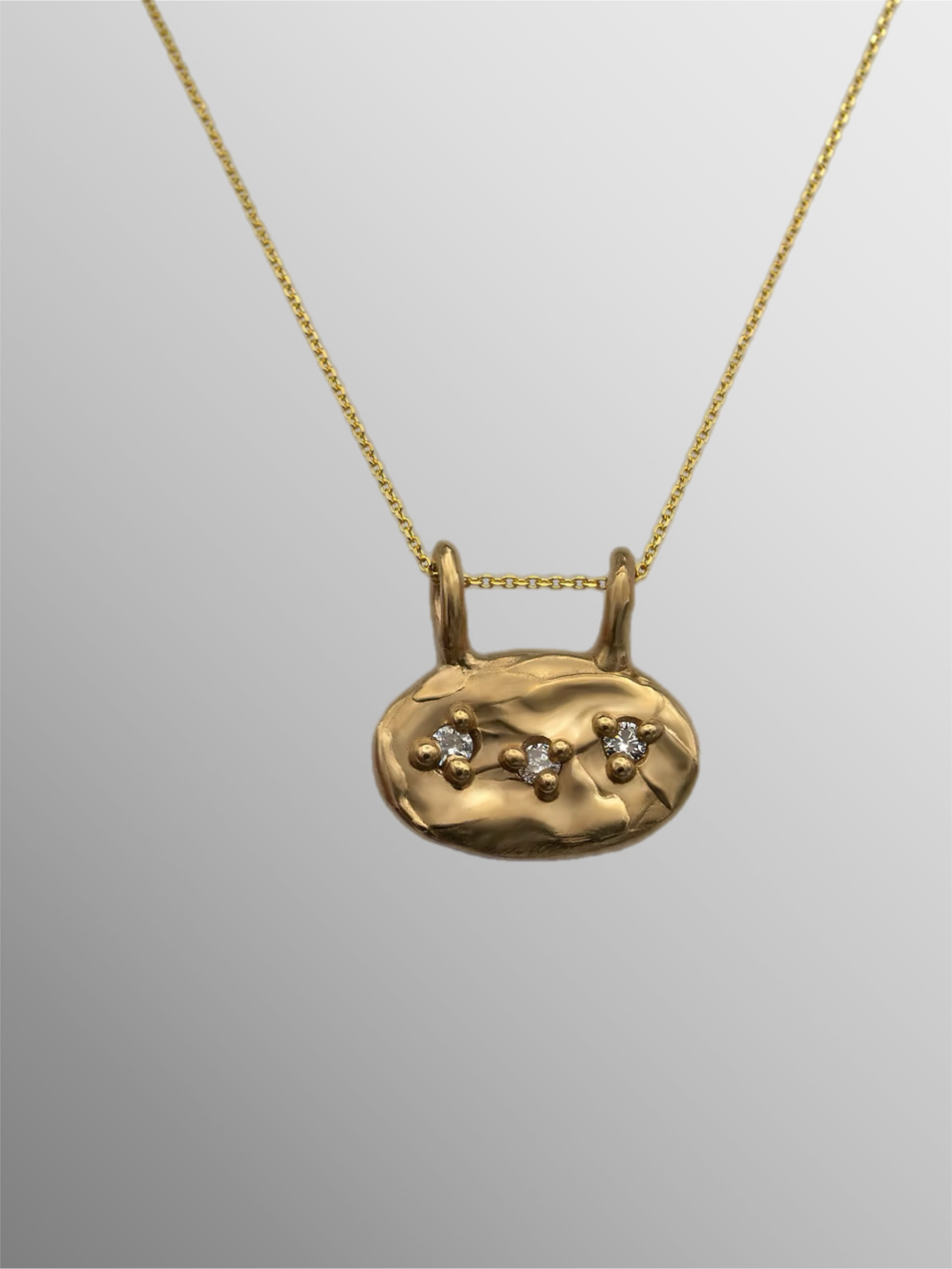 Oval bronze pendant with three zircon stones by Floret Gioielli.