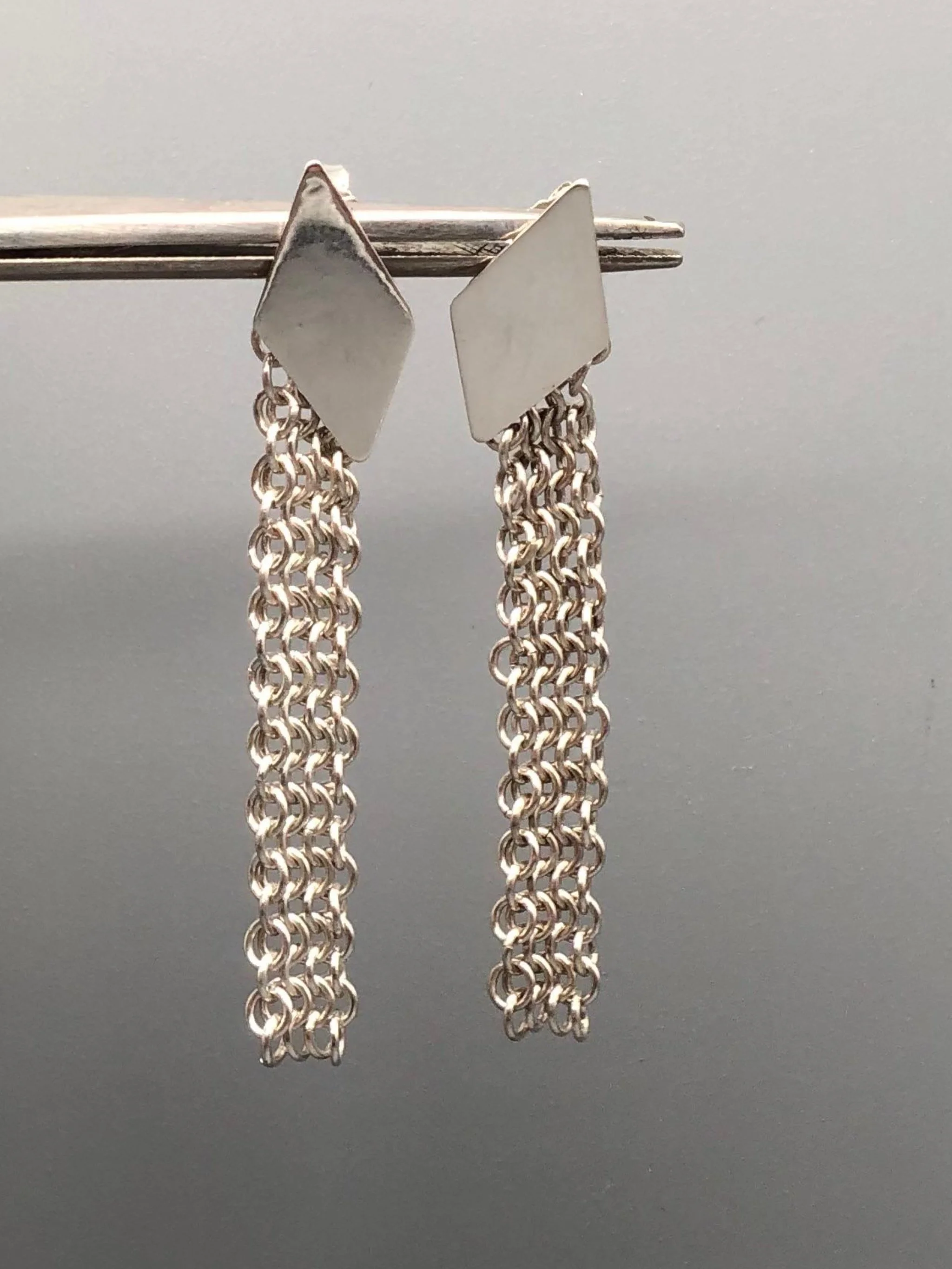 Sterling silver mesh earrings by Ariadna Segafredo for Crepundia Gioielli, featuring a geometric silver top and long handcrafted woven silver chain.