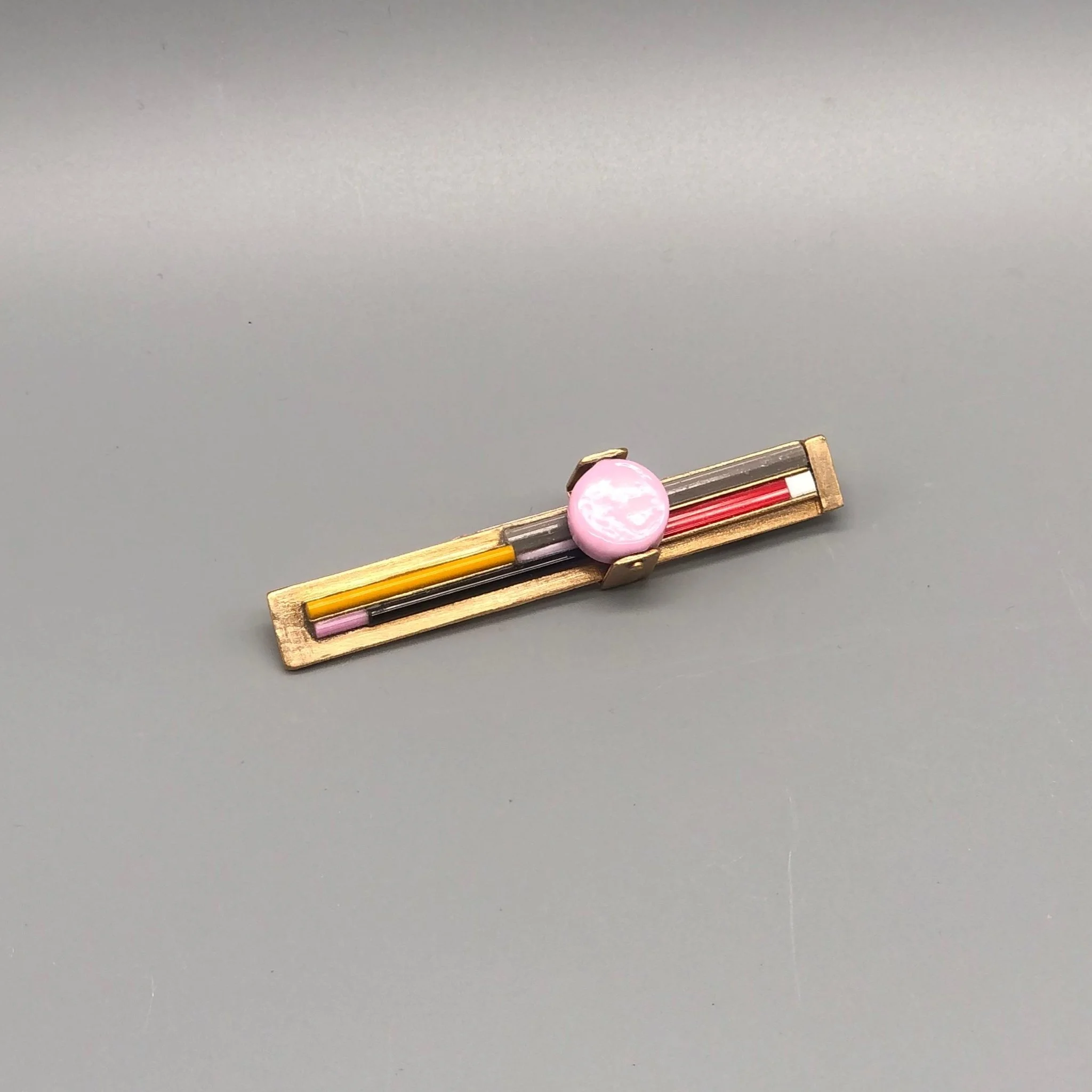 Spilla in bronzo con elemento in vetro, composizione lineare e variazione cromatica.
EL Gioielli — Crepundia Gioielli Bologna.

Bronze brooch with glass element, linear composition and chromatic variation.
EL Gioielli — Crepundia Gioielli Bologna.