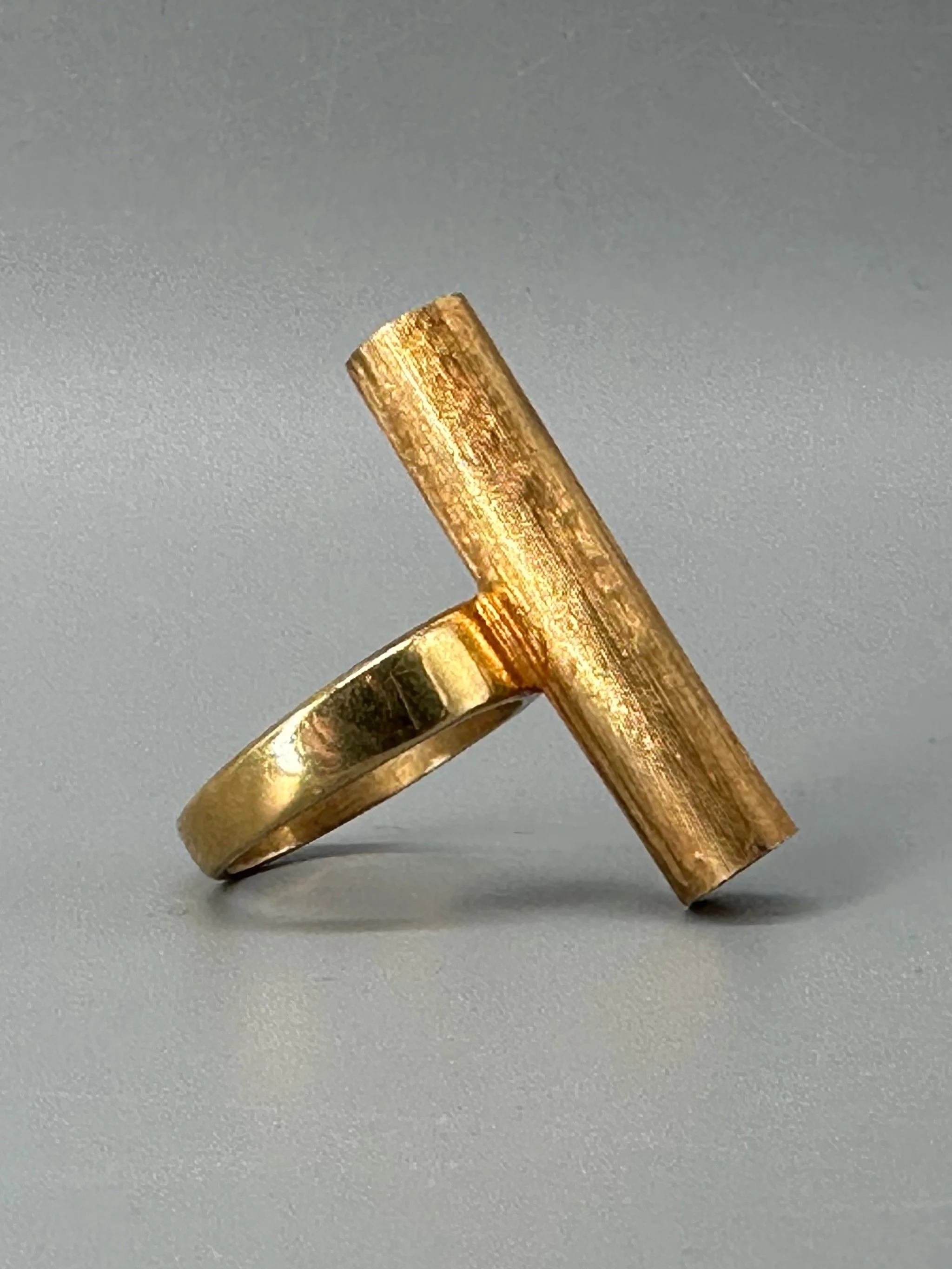 Anello Rough Tube di HoAsen Jewelry in argento dorato satinato, con elemento tubolare inciso.  Rough Tube ring by HoAsen Jewelry in satin-finished gold-plated silver, with a textured tubular element.